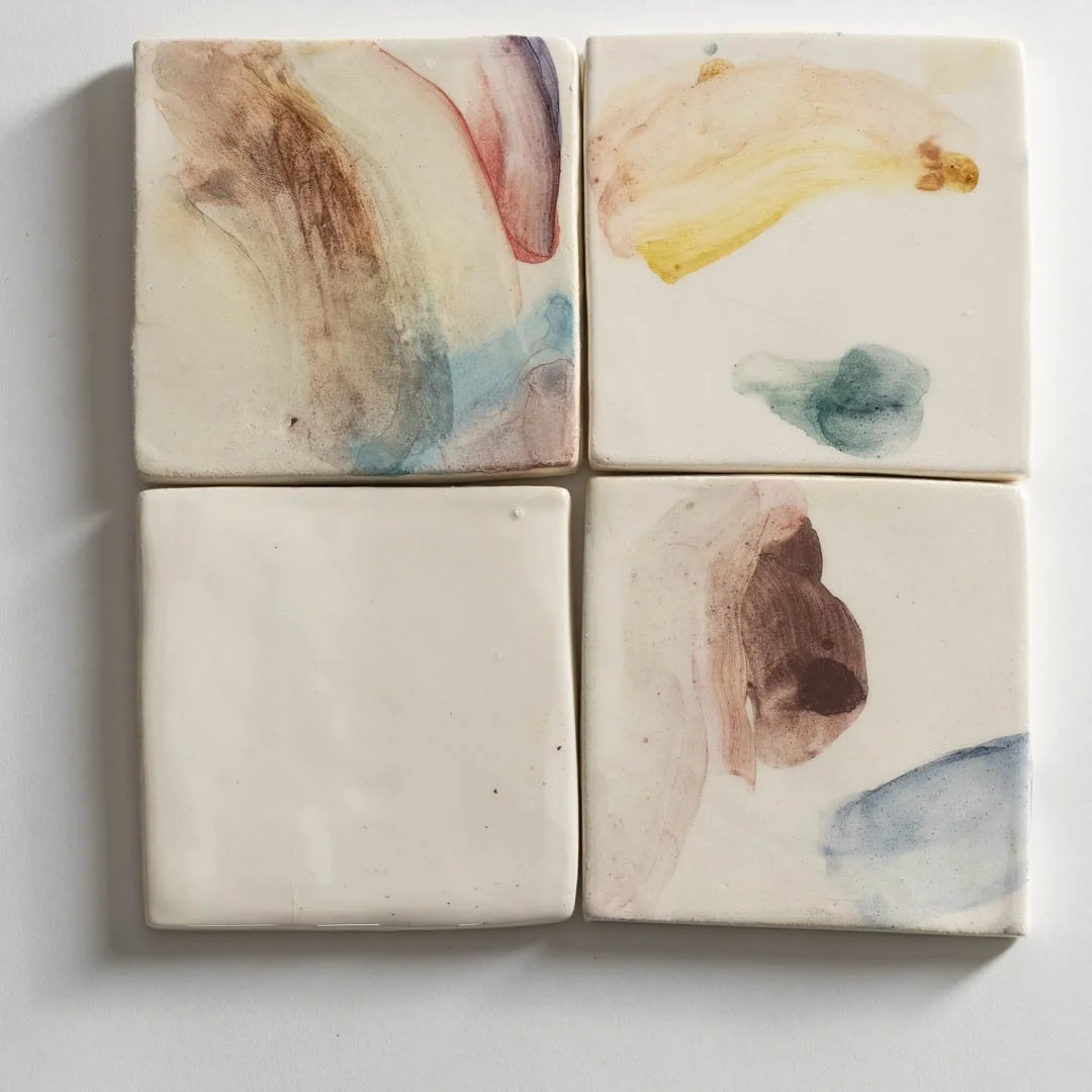 Set of four square ceramic tiles with abstract watercolor-style paint strokes in various colors.