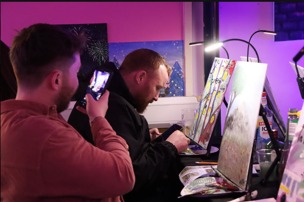 Man taking picture of his friend and their painting