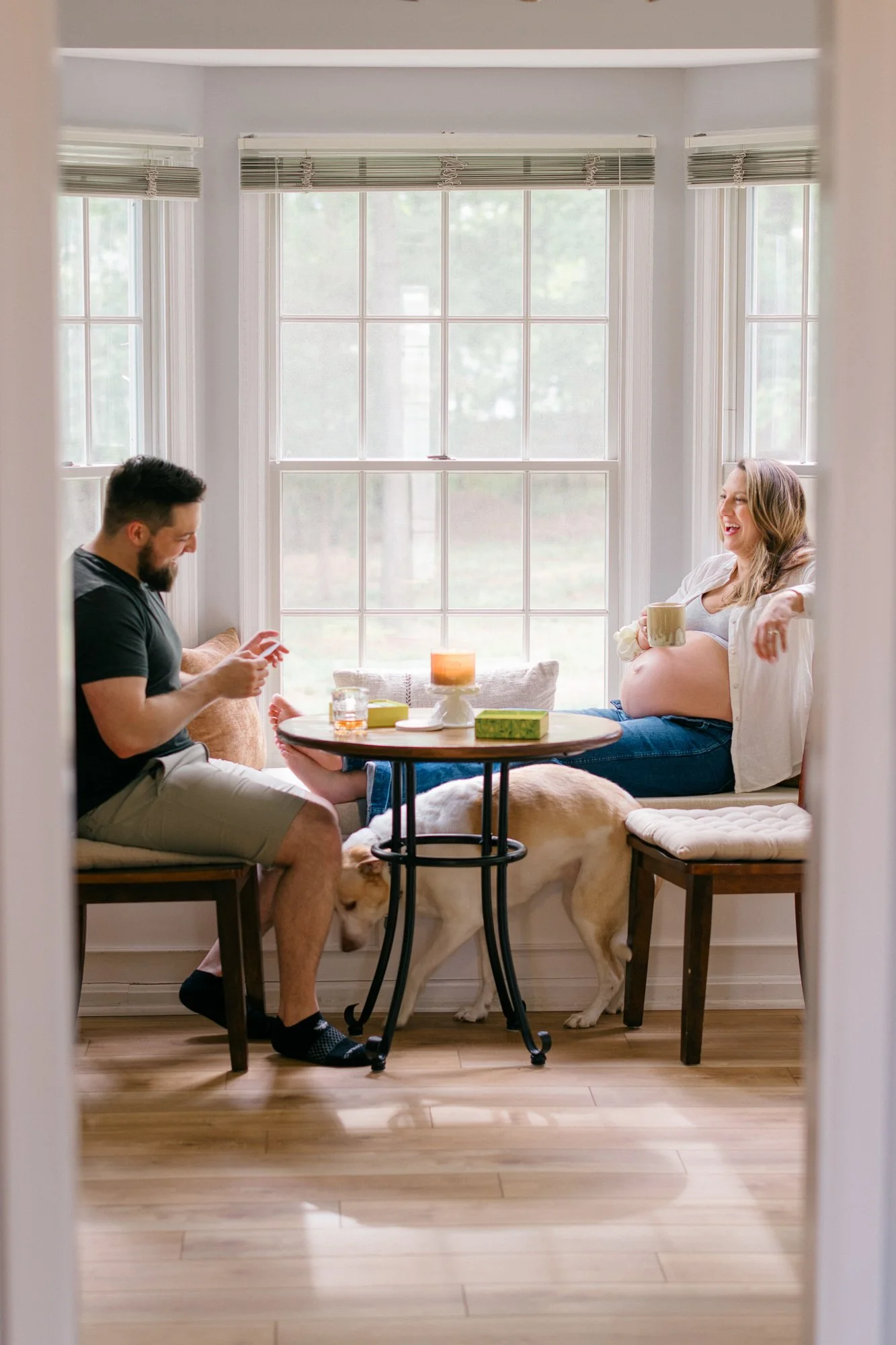  Expecting parents relax at their kitchen nook with their dog nearby during a documentary maternity session in Sterling, Virginia. 