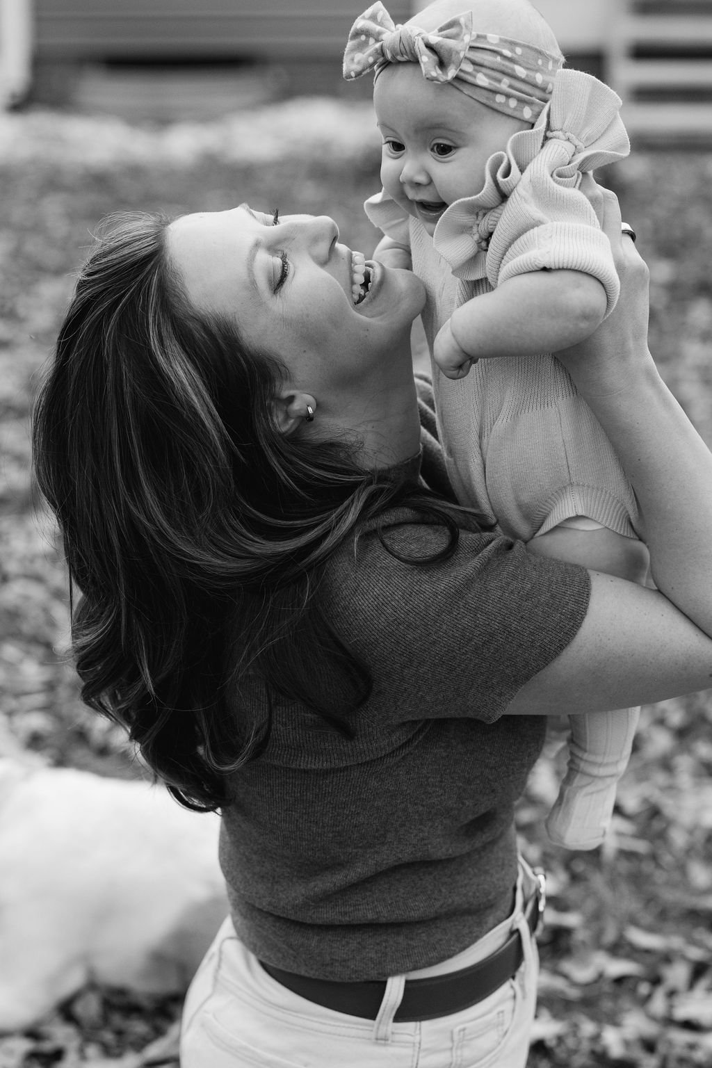  Mother lifting her baby into the air outdoors in the backyard during a documentary family session in Sterling, Virginia. 