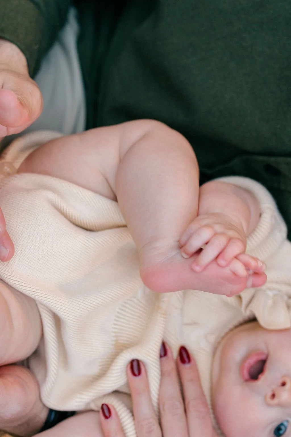  Baby playing with her feet while sitting outside on the front porch during a documentary family session in Sterling, Virginia. 