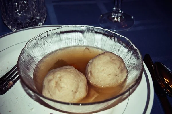 Two matzo balls in a bowl of broth served at a Passover seder dinner, documented as a traditional Passover food detail by Mel Usry Photography Northern Virginia.
