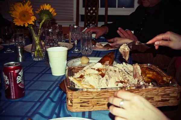 Family members reach across the Passover seder table to share a basket of chicken and other dishes, captured candidly by documentary family photographer Mel Usry Photography Northern Virginia.