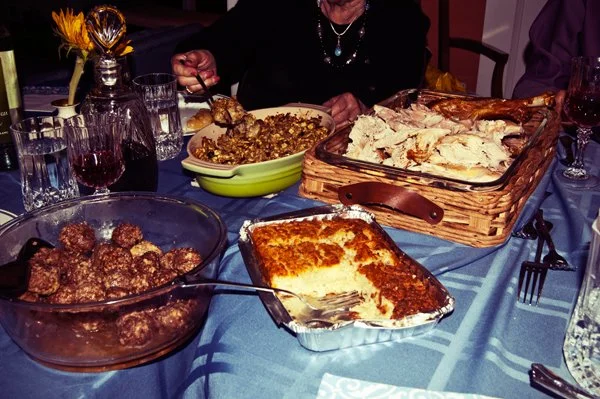 Multiple dishes including meatballs, chicken, vegetables, and kugel spread across the Passover seder table, documented during a multi-generational family gathering by Mel Usry Photography Virginia.