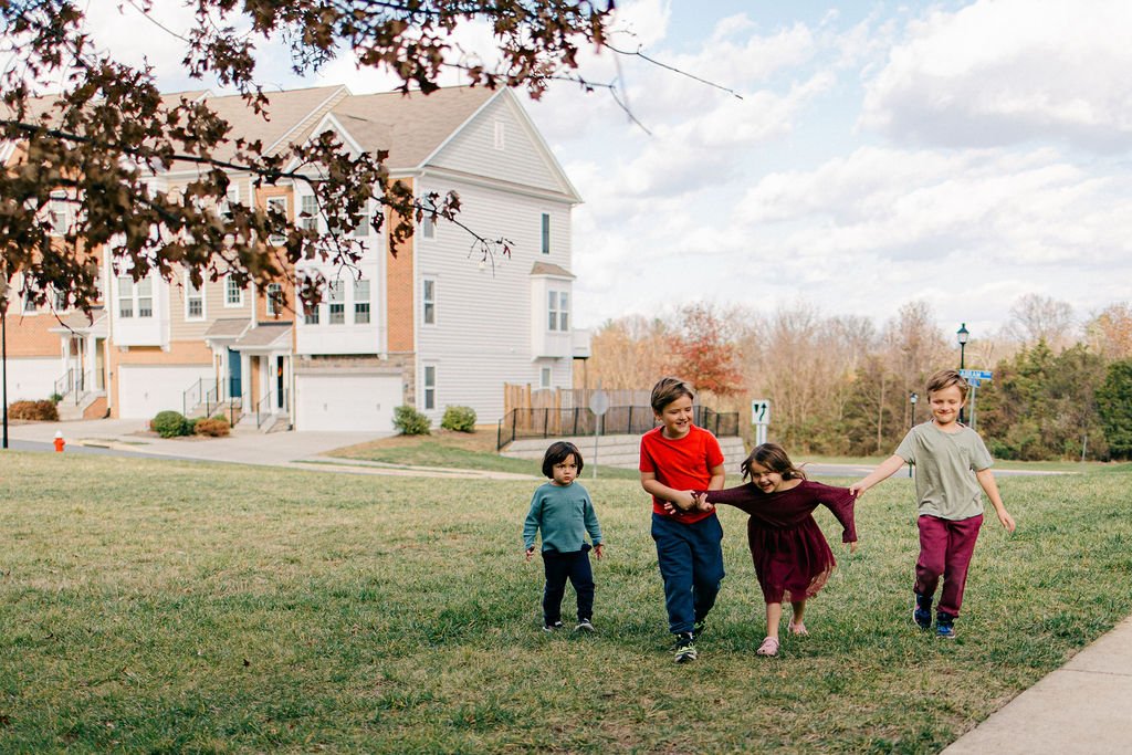 Children walking together outdoors during a documentary family session in Ashburn, Virginia.
