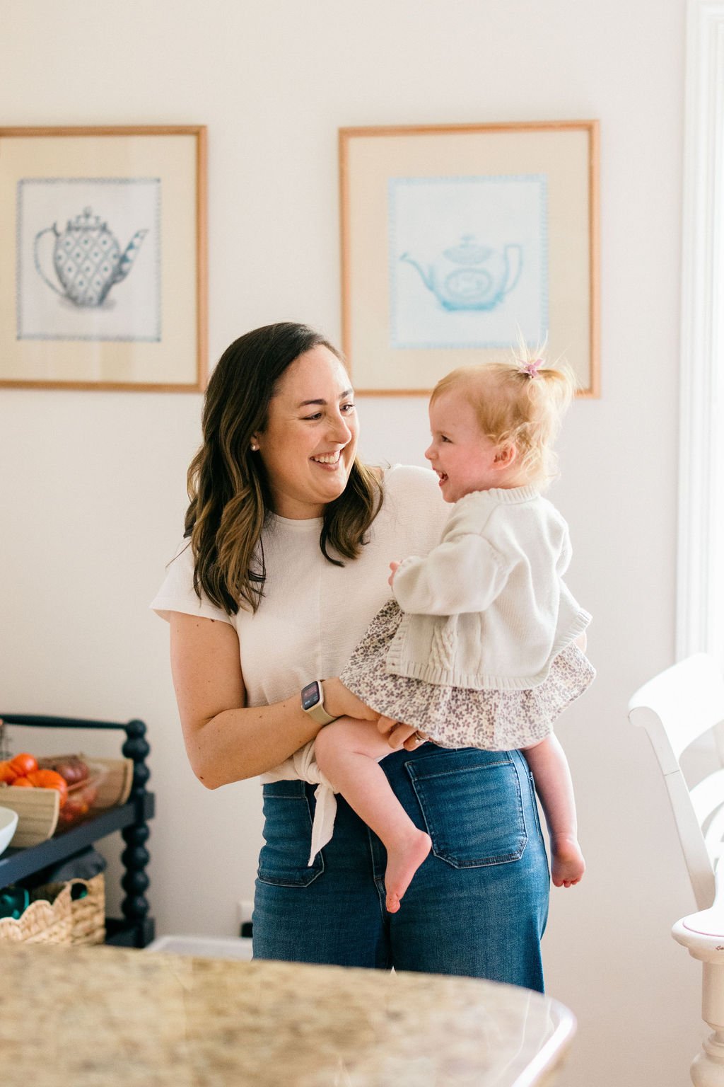 Mother holding her toddler in a bright kitchen during a documentary family photography session in Alexandria, Virginia.