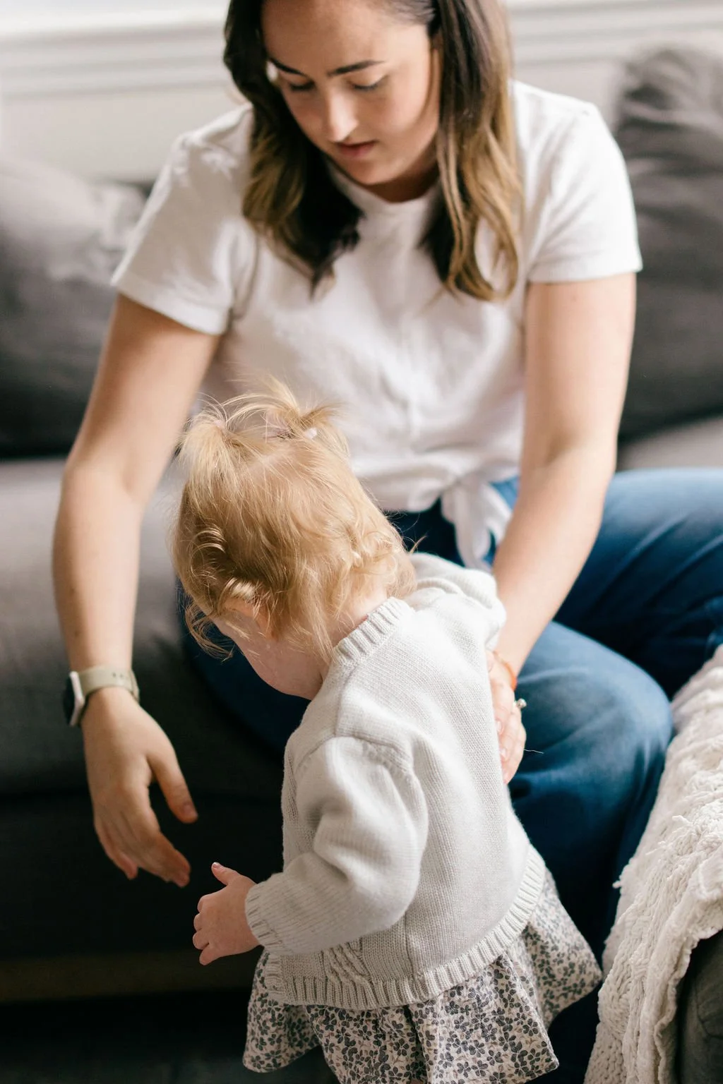 Mother helping her toddler get ready to go outside during an in-home documentary family session in Alexandria, Virginia.