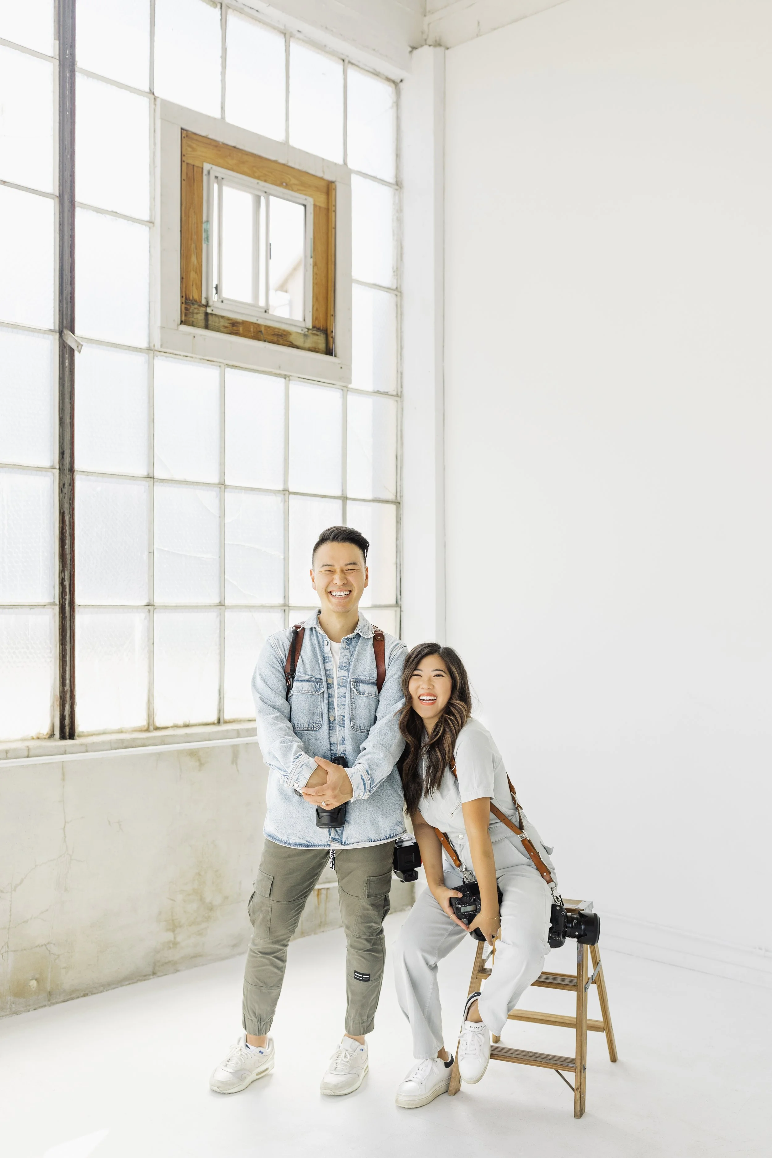 Smiling husband and wife Seattle photographers and videographers ready to capture your big day