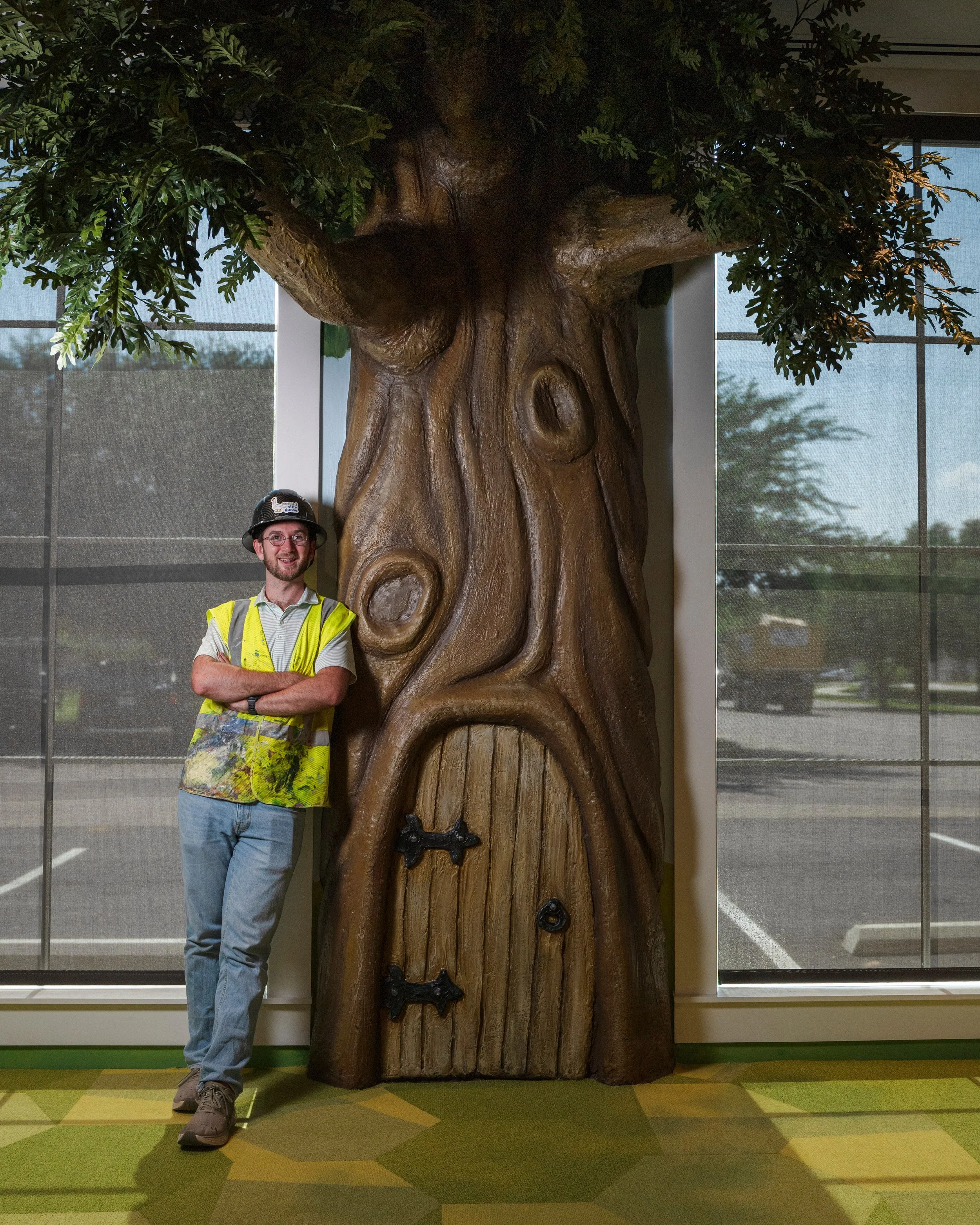 Banks Compton standing beside the sculptural reading tree he created for the children's section of Foley Community Library in Foley, Alabama.