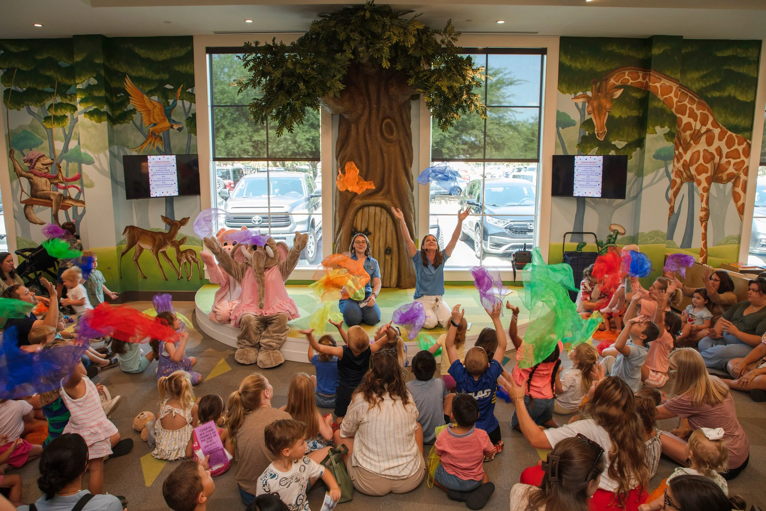 Children and families gathered around Banks Compton's sculptural reading tree and murals at Foley Community Library in Foley, Alabama.