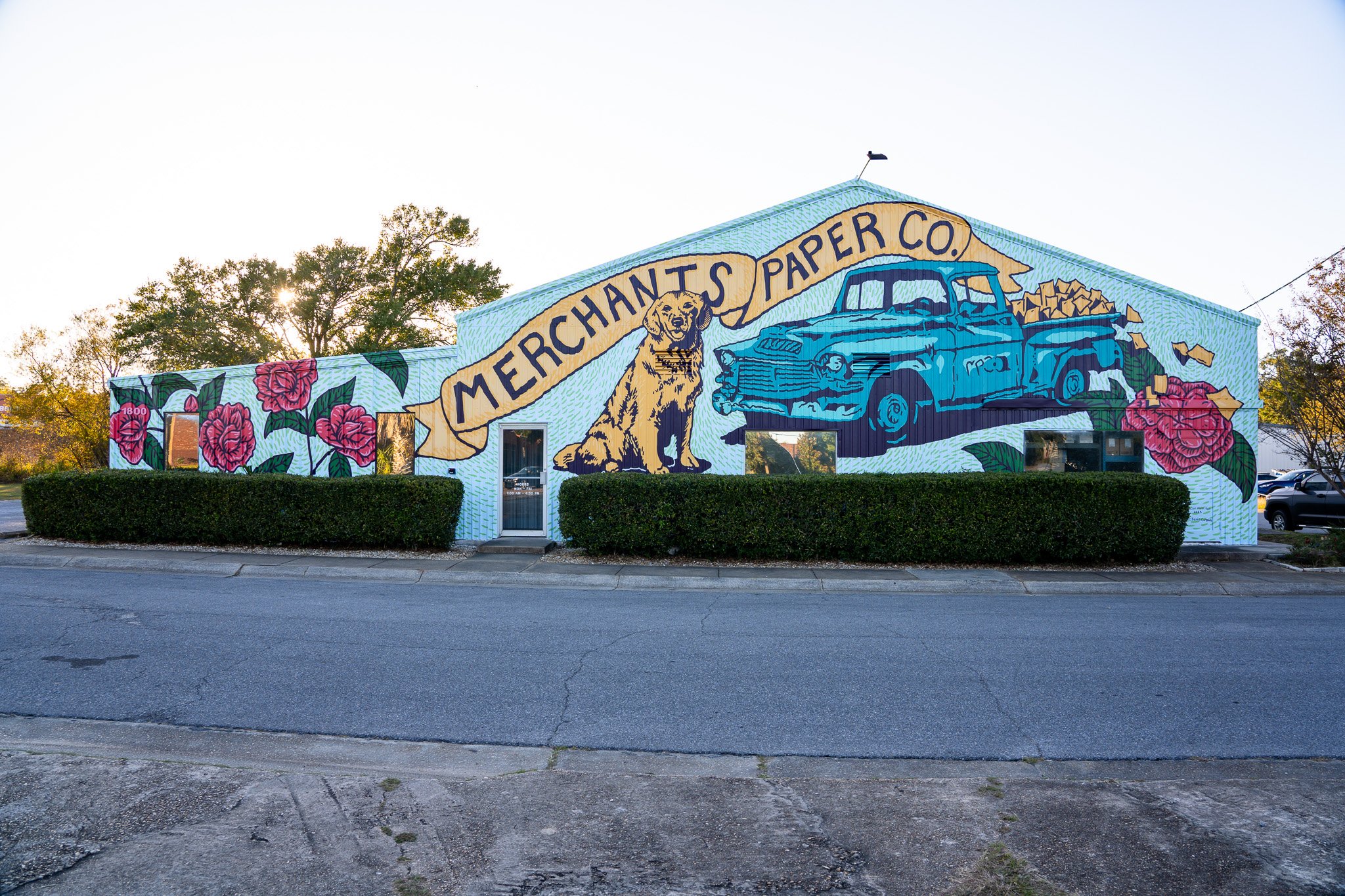 Merchants Paper Company mural by Banks Compton in Pensacola, Florida, featuring a vintage delivery truck, golden retriever, paper products, and camellias.