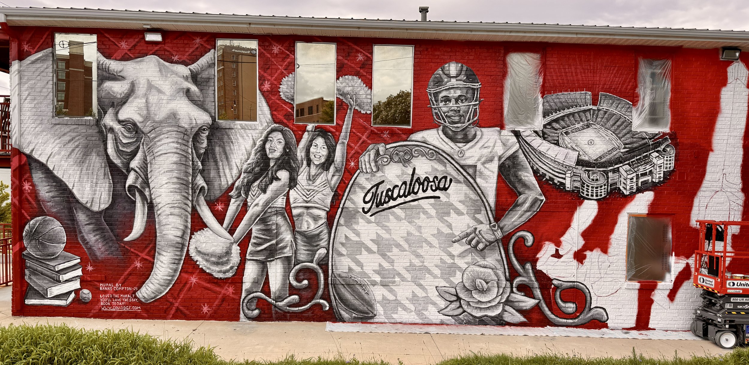 Colorful mural on a brick building featuring an elephant, two cheerleaders, a football player holding a large sign with 'Tucaloosa' written on it, and a stadium. The mural is in black, white, and gray with red background accents.