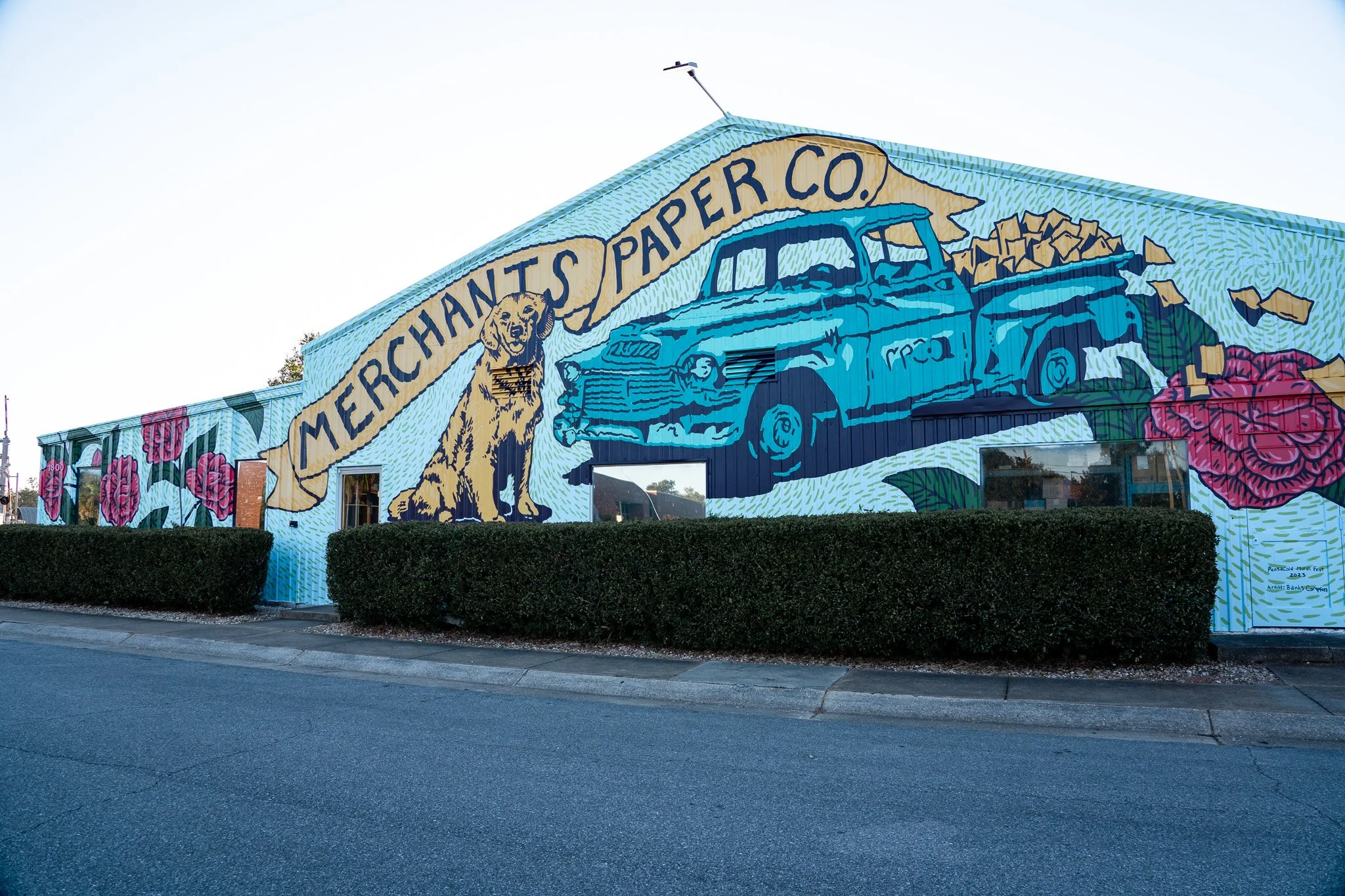 Merchants Paper Company mural by Banks Compton in Pensacola, Florida, featuring a vintage delivery truck, the family dog Piper, flying paper products, and Southern camellias.