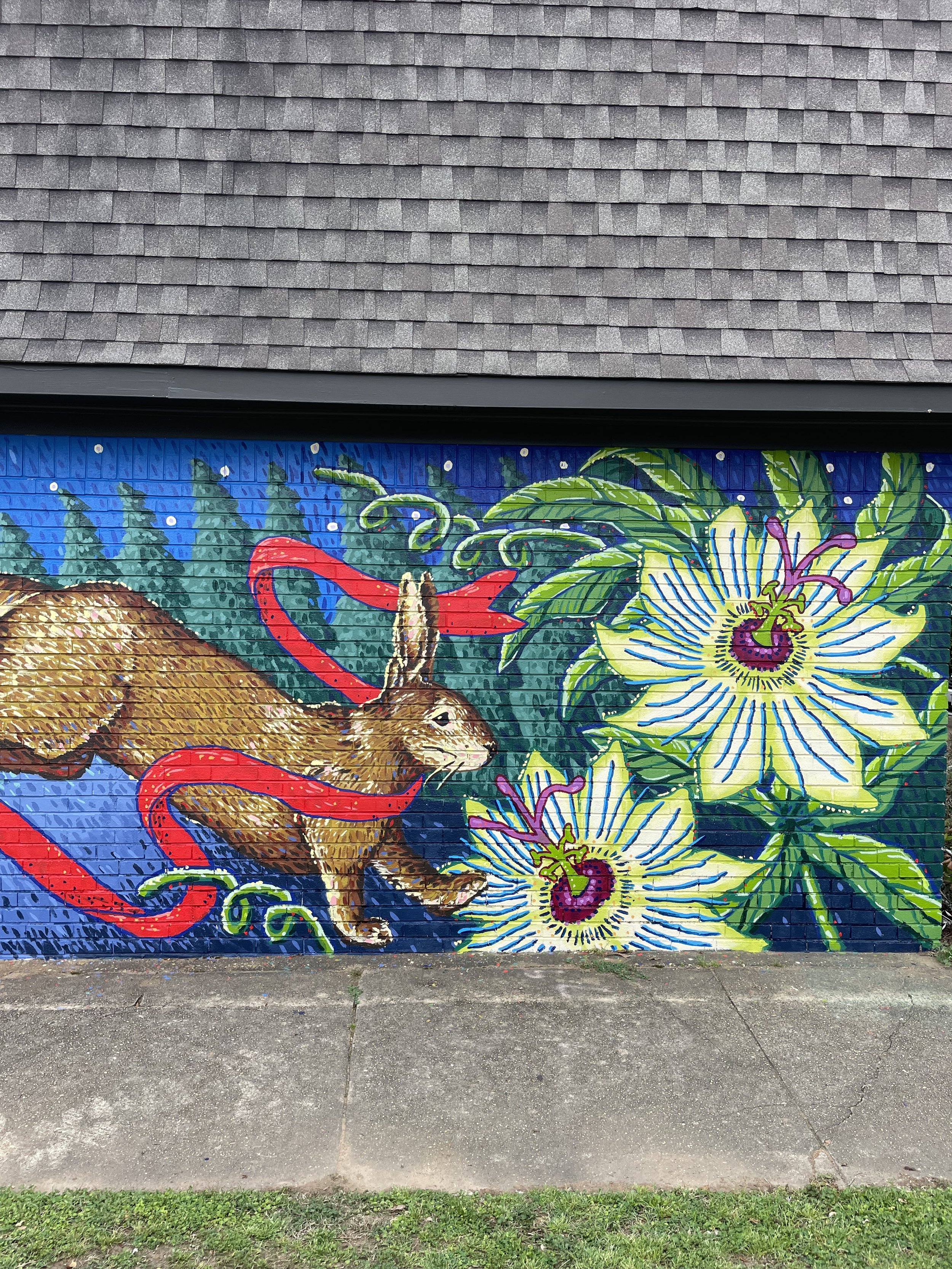 Colorful mural on a brick wall depicting a rabbit, flowers, and swirling patterns with a starry night background.
