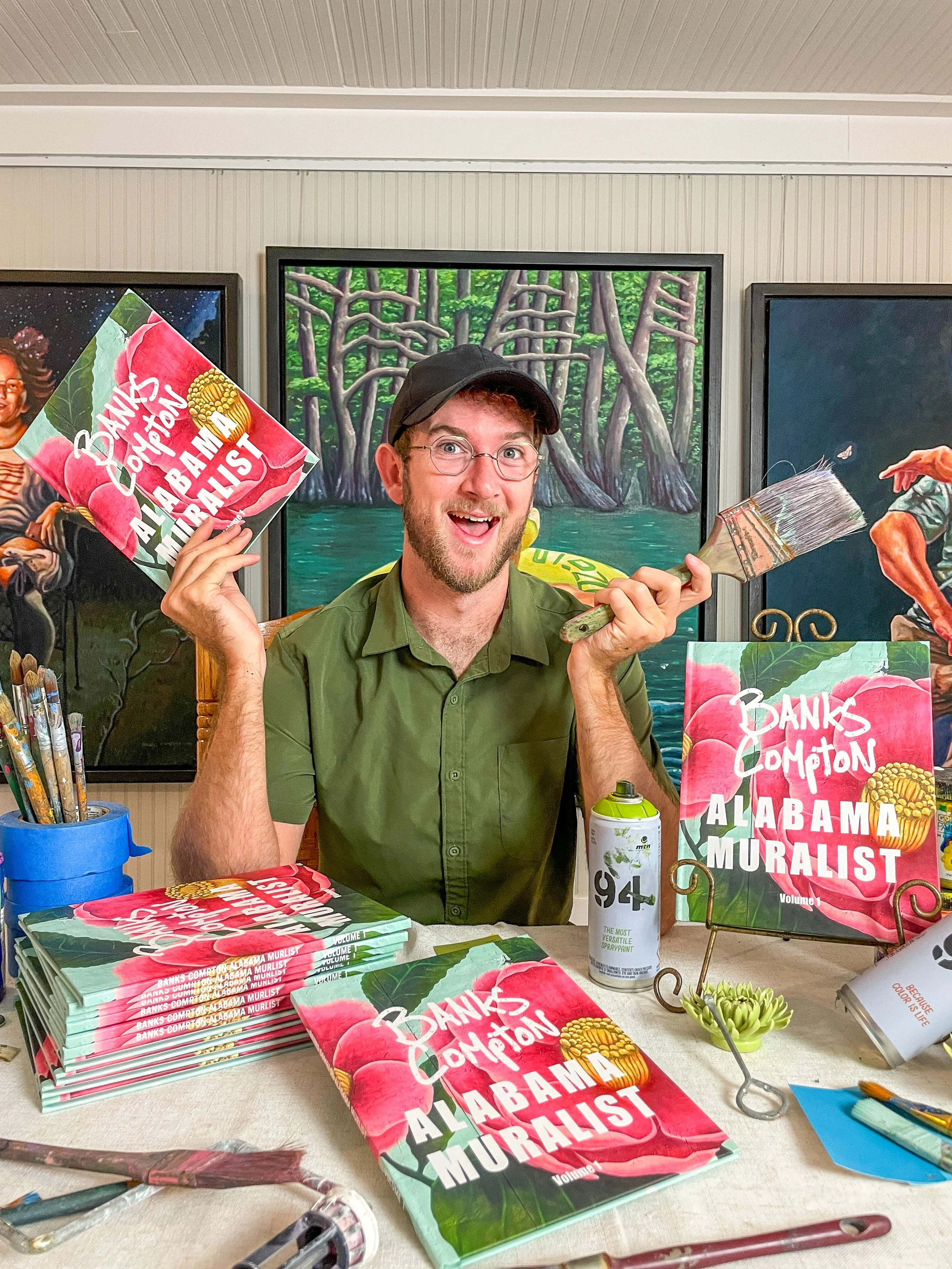 Banks Compton holding copies of his Alabama Muralist book, a collection documenting his murals and public art projects across Alabama and beyond.