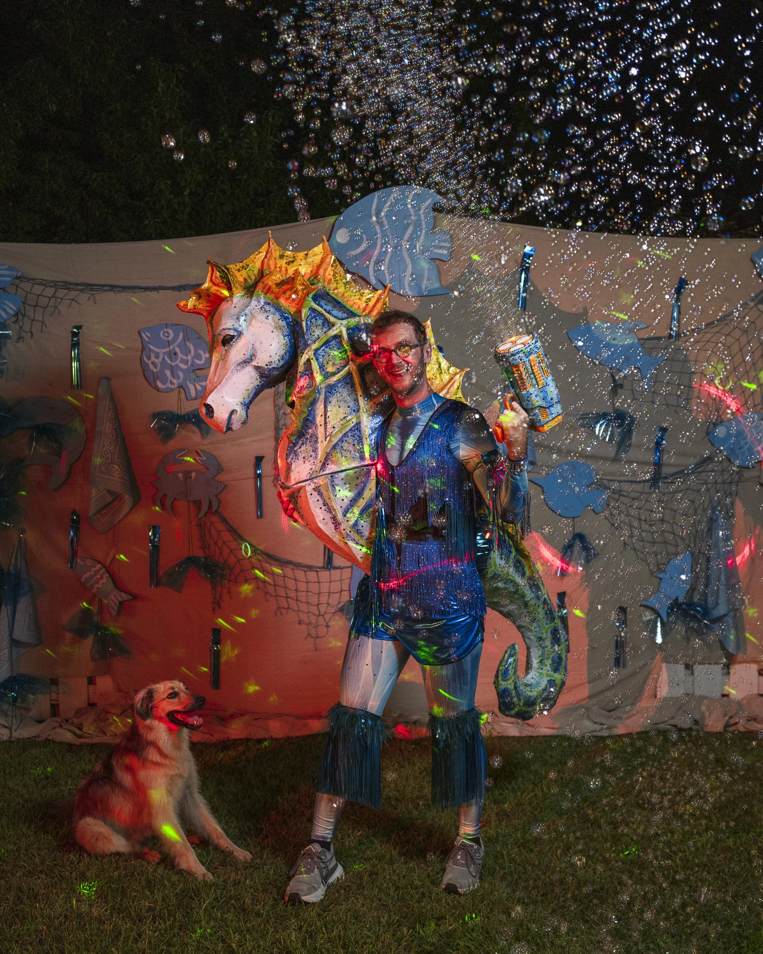 Banks Compton wearing his handmade papier-mâché seahorse sculpture with painted details, rhinestones, and shimmering fringe.