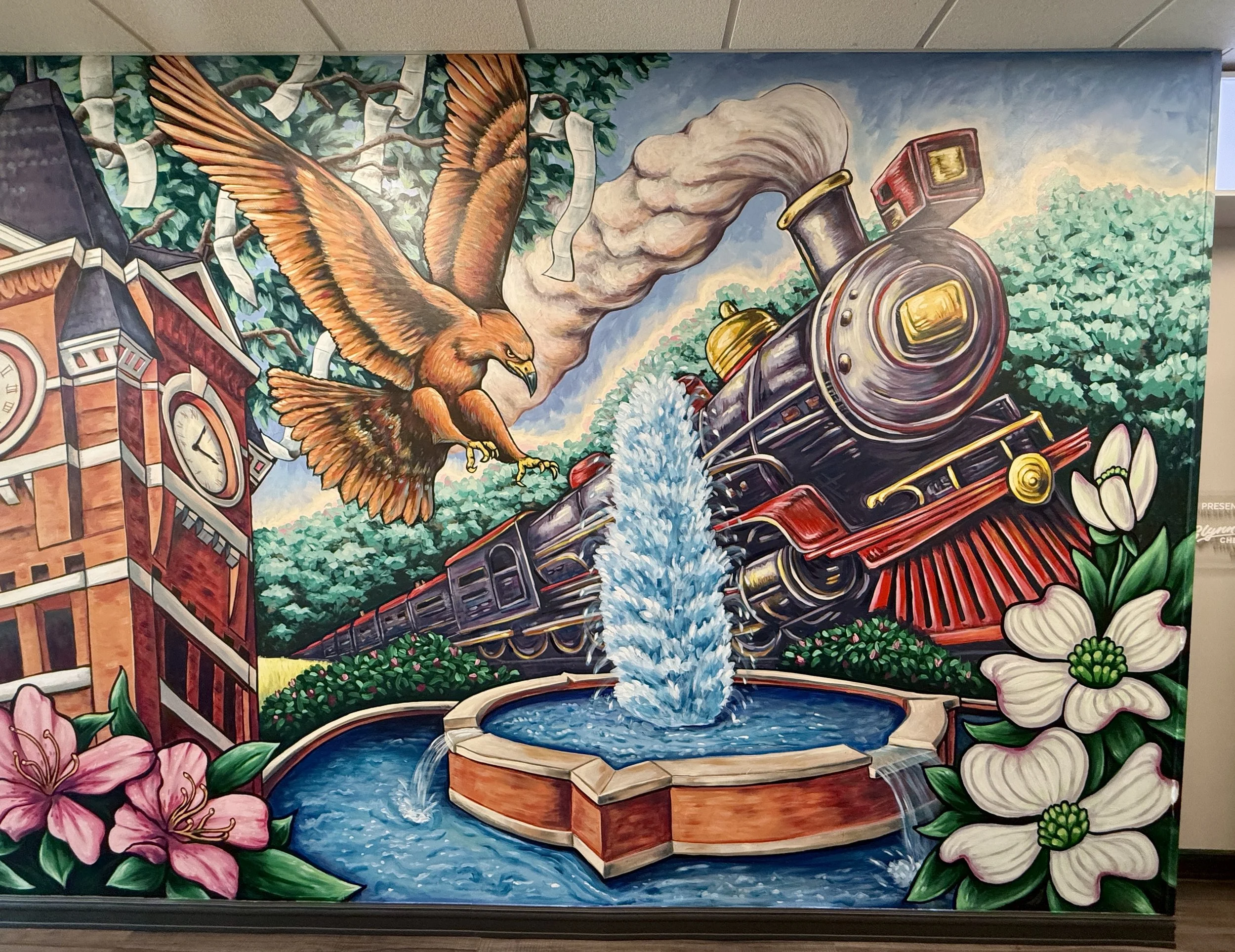 A colorful mural depicting a steam train passing a fountain, surrounded by flowers and an eagle soaring above, with a clock tower behind the building.