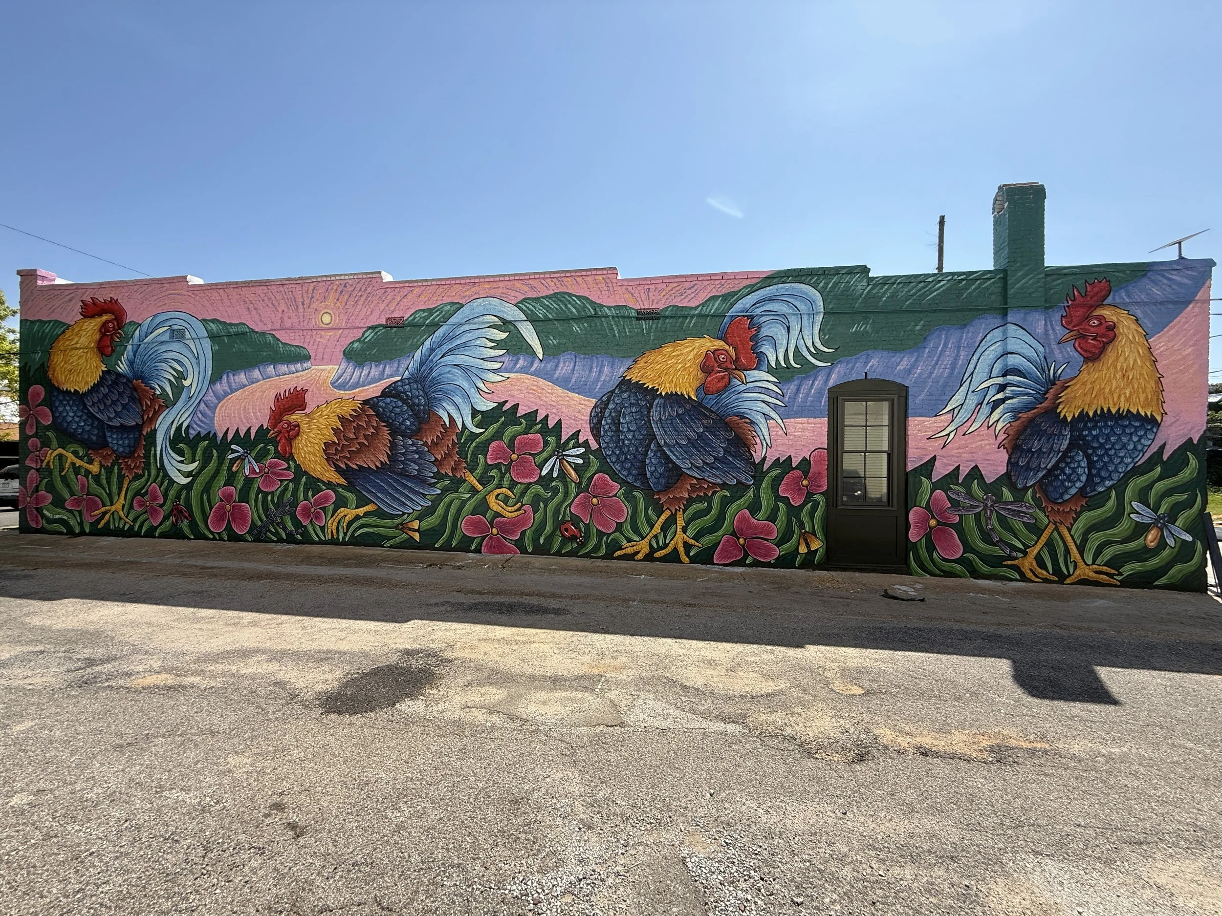 Rooster Day mural by Banks Compton on the Chanticleer Center in downtown Demopolis, Alabama, featuring four colorful roosters, flowers, insects, and local landscape imagery.