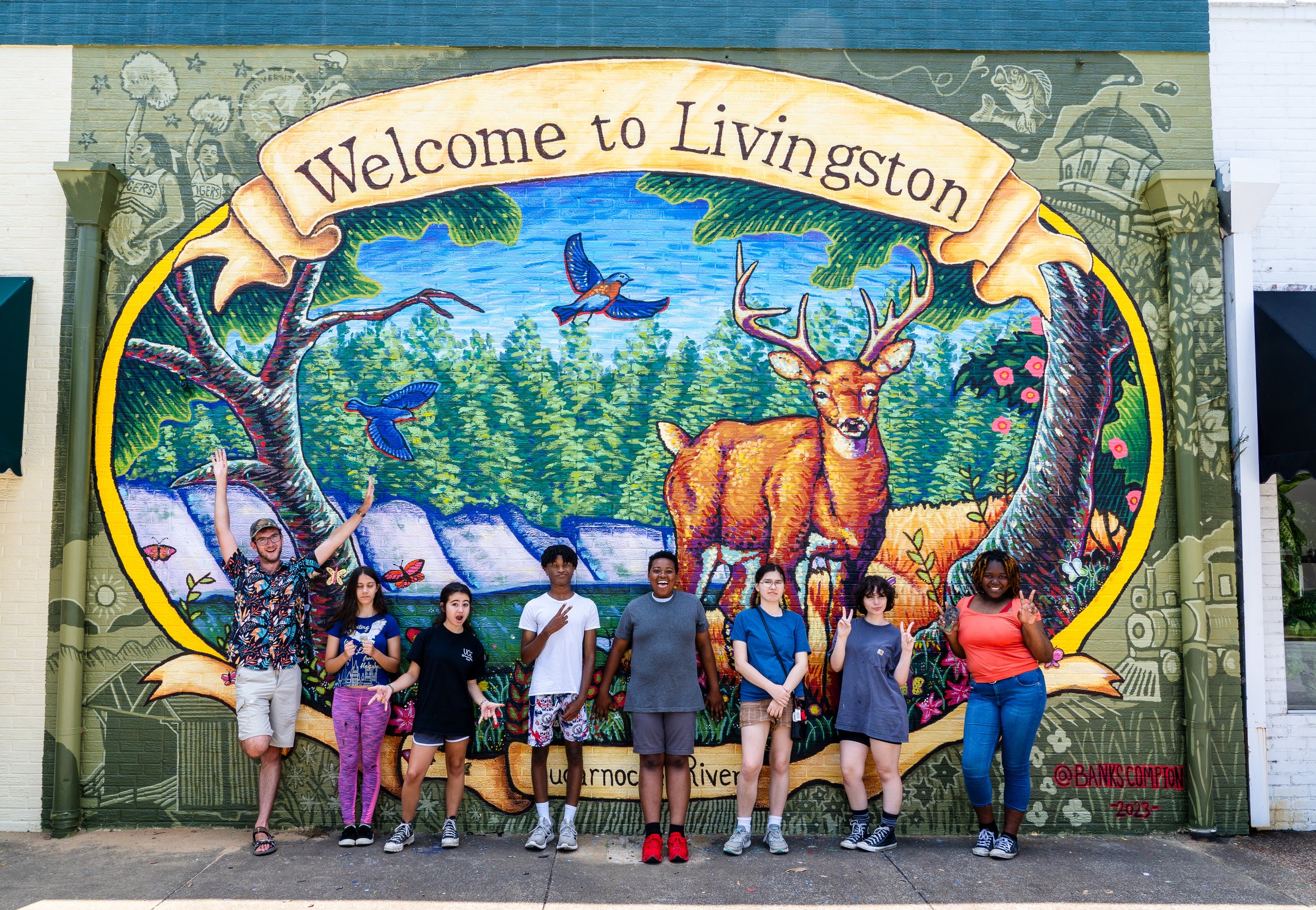 Community mural by Banks Compton in Livingston, Alabama, featuring a white-tailed deer, Sucarnoochee River landscape, and University Charter School students.