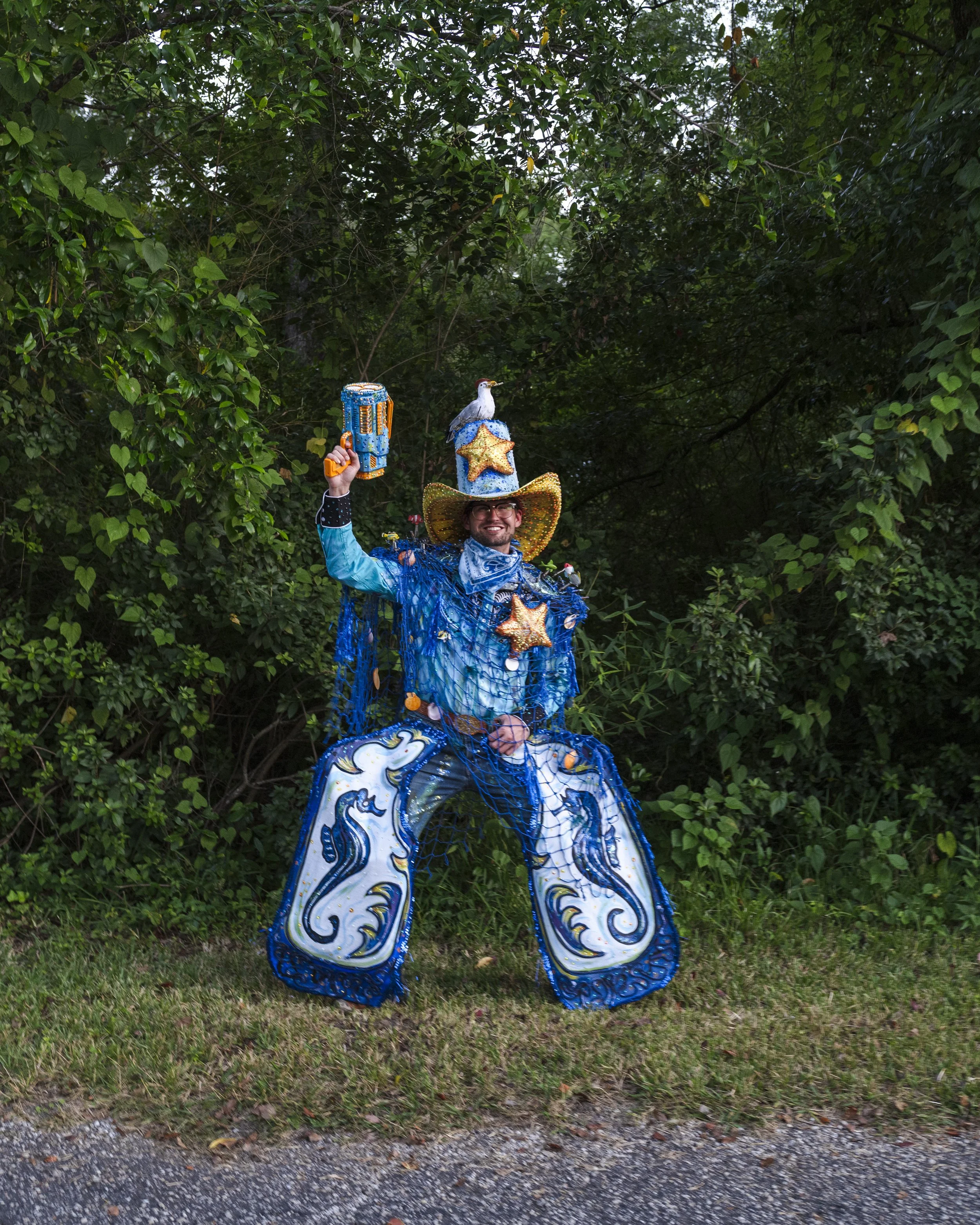 Banks Compton wearing the handmade underwater cowboy costume featuring blue fringe, starfish, seahorse panels, a decorated cowboy hat, and bubble gun.