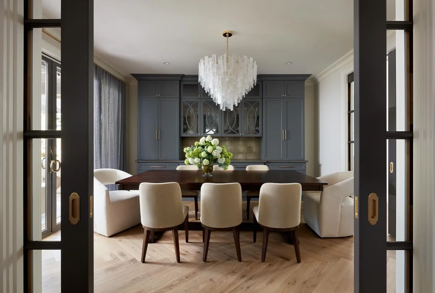 This dining room brings the WOW! The French oak herringbone floors, the charcoal gray glass doors, the custom built in, the hydrangeas that go everywhere and THAT chandelier! Pour me an old fashioned and I could relax here for days. 

Architecture: @