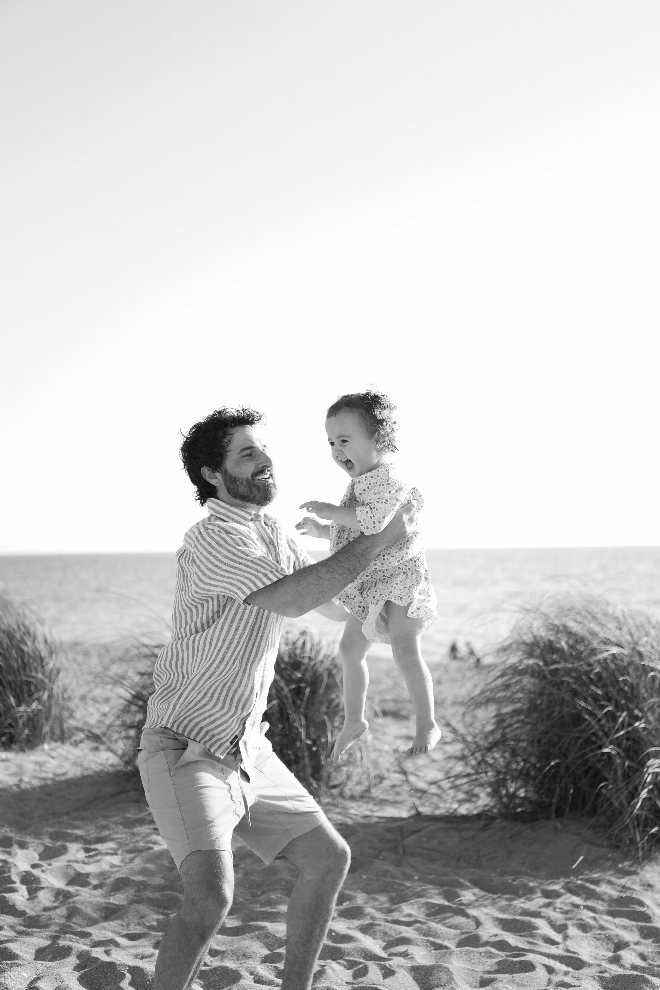family-beach-photoshoot-venice-florida-dad-throwing-daughter-black-and-white.jpg