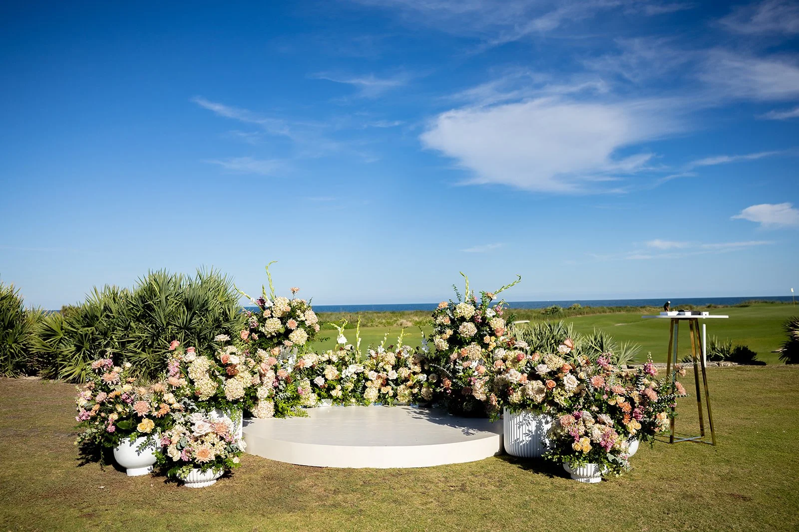 ceremony/ alter for wedding. large urn flower arrangement on a custom round stage, at hammock beach resort and spa.