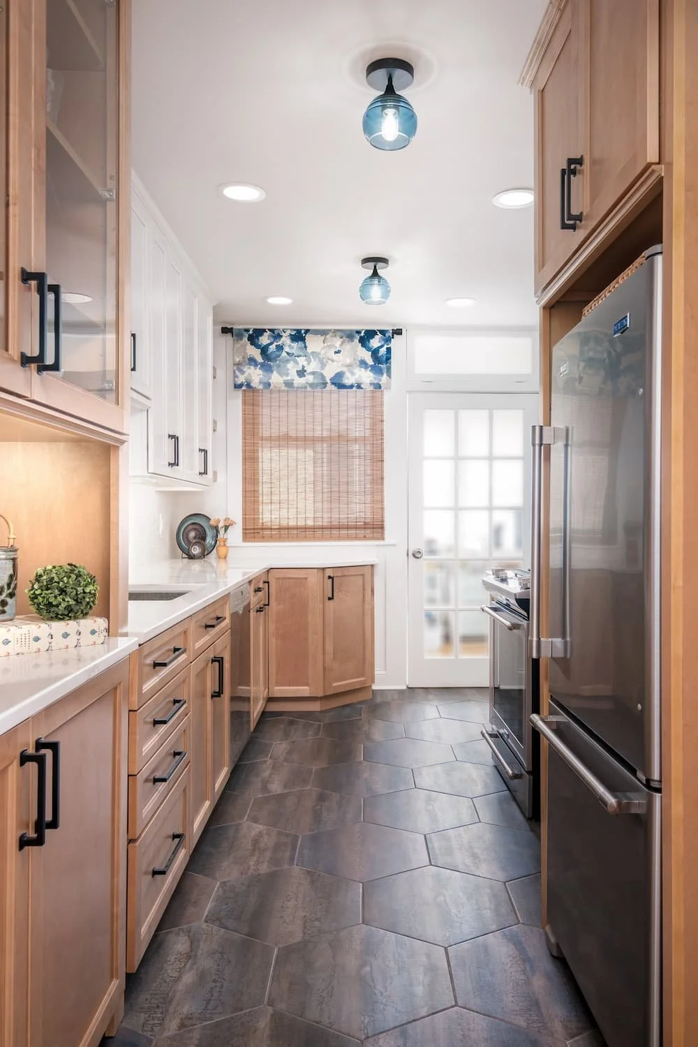Brightly lit kitchen designed with light colored wood cabinets and dark floors