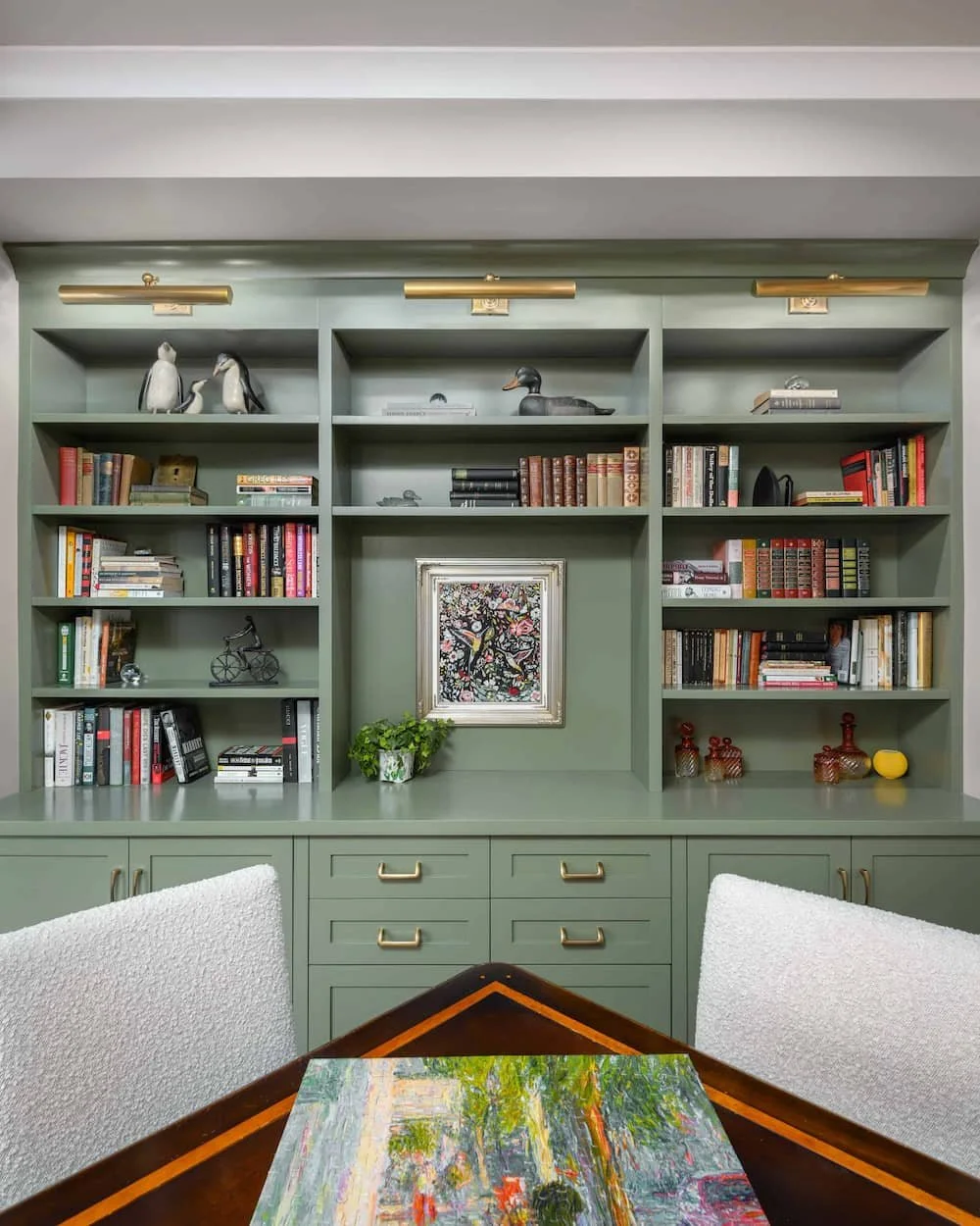 built in green shelf system with books and art organized by an interior decorator