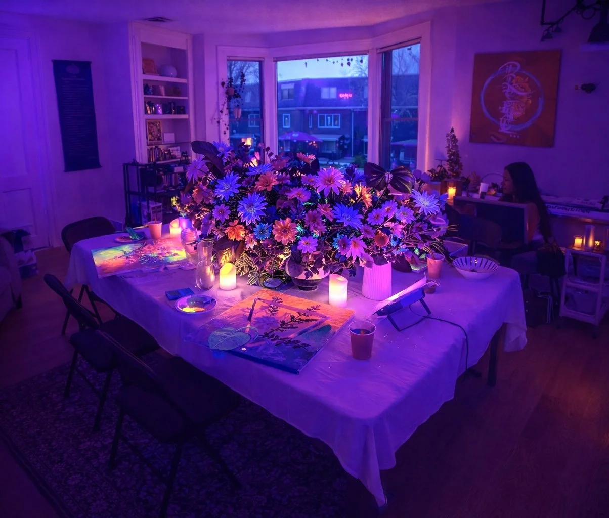 A dining room decorated with colorful LED lights, a large floral centerpiece, and candles on a table covered with a white tablecloth during evening time.