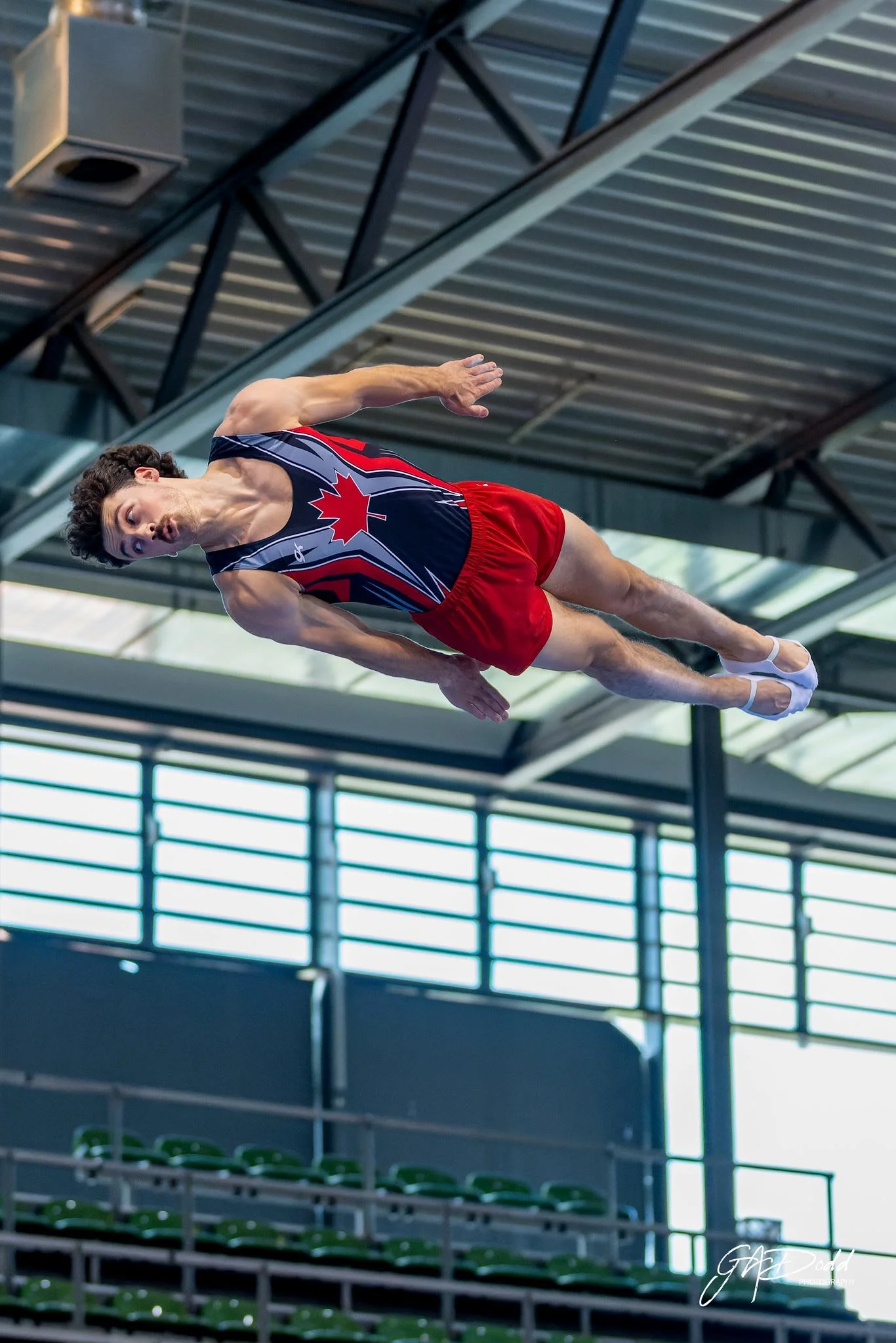 Male trampolinist performs a skill in a team canada uniform