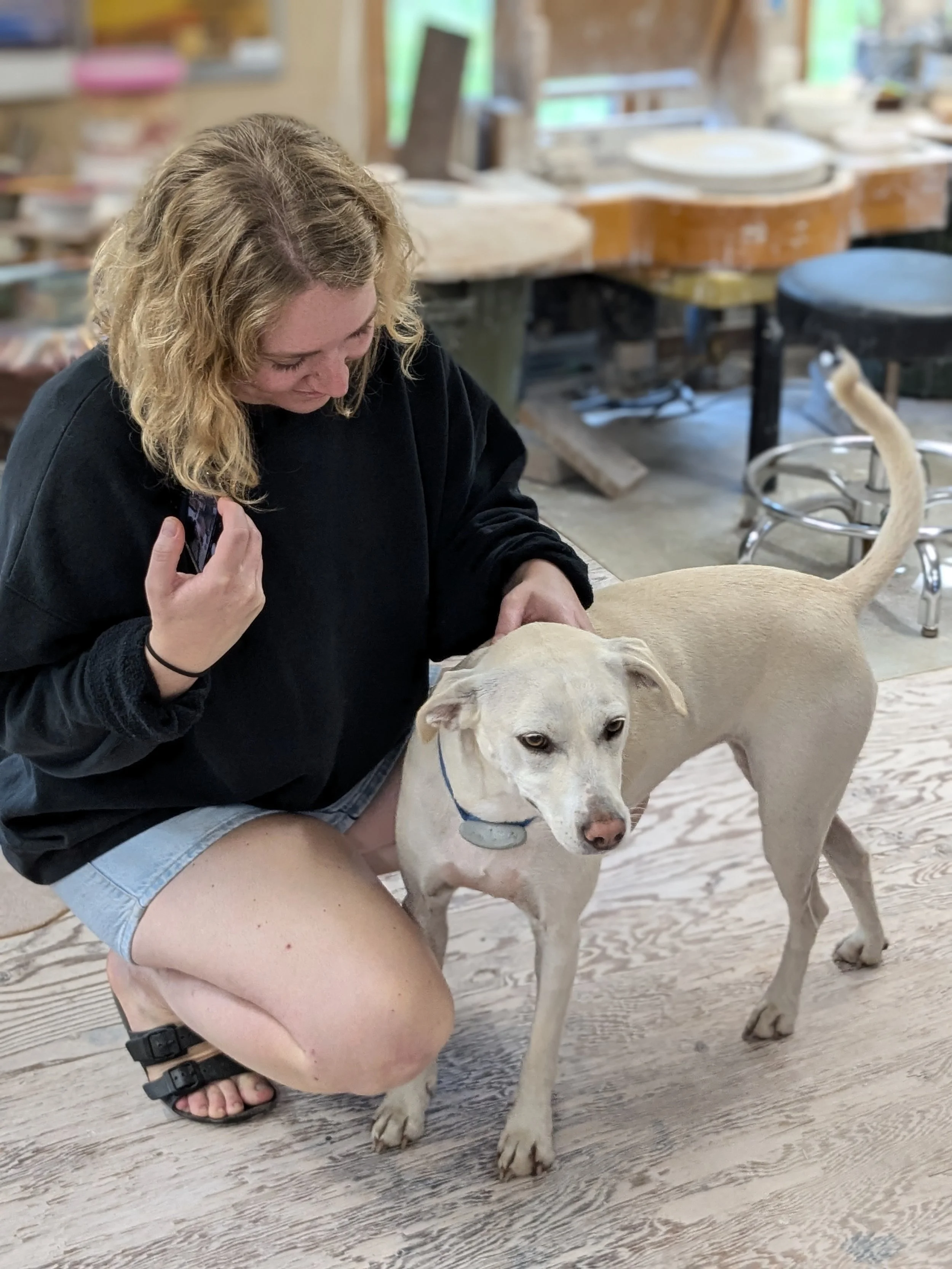 Blonde woman with white dog at pottery studio