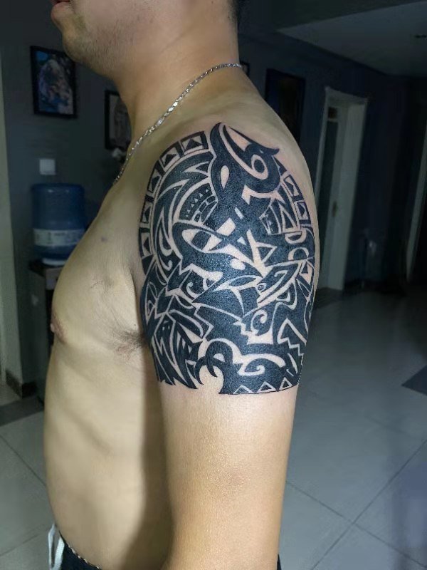 Person with detailed tribal tattoo on upper arm