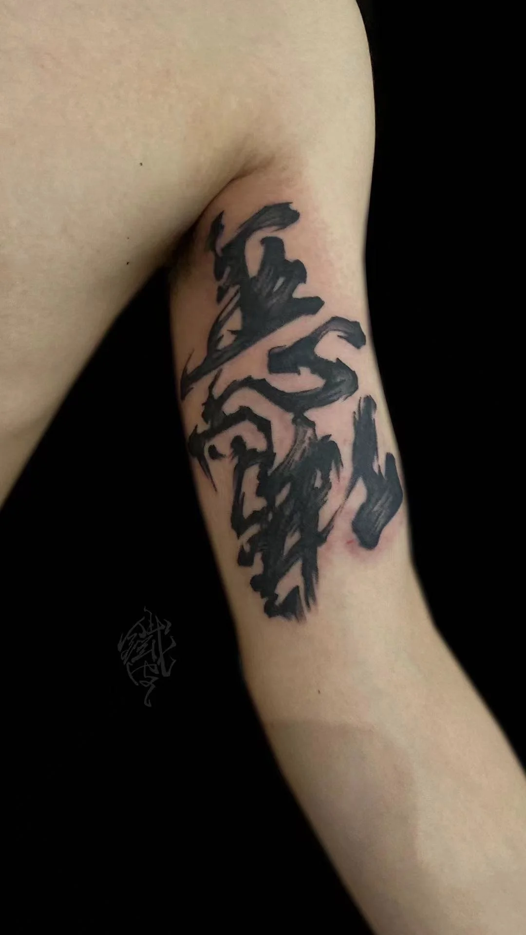 Black ink calligraphy tattoo on arm