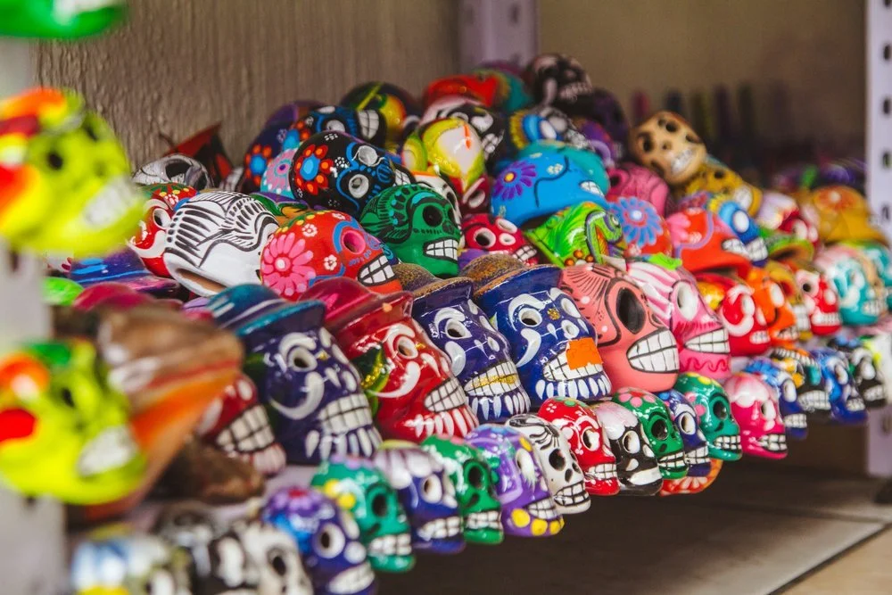 Colorful display of painted sugar skull souvenirs arranged on shelves.
