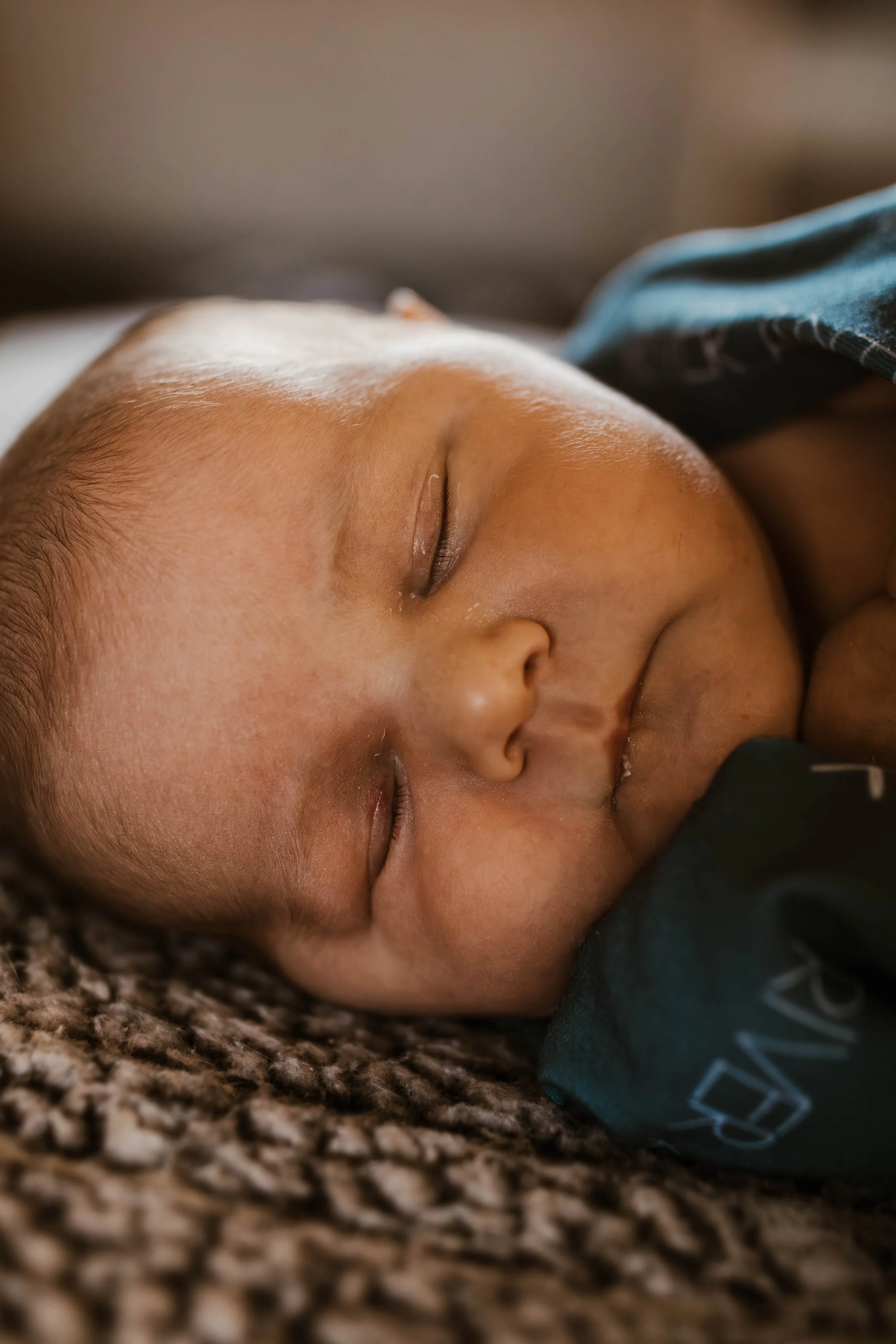 Close-up of a sleeping baby lying on a textured blanket.