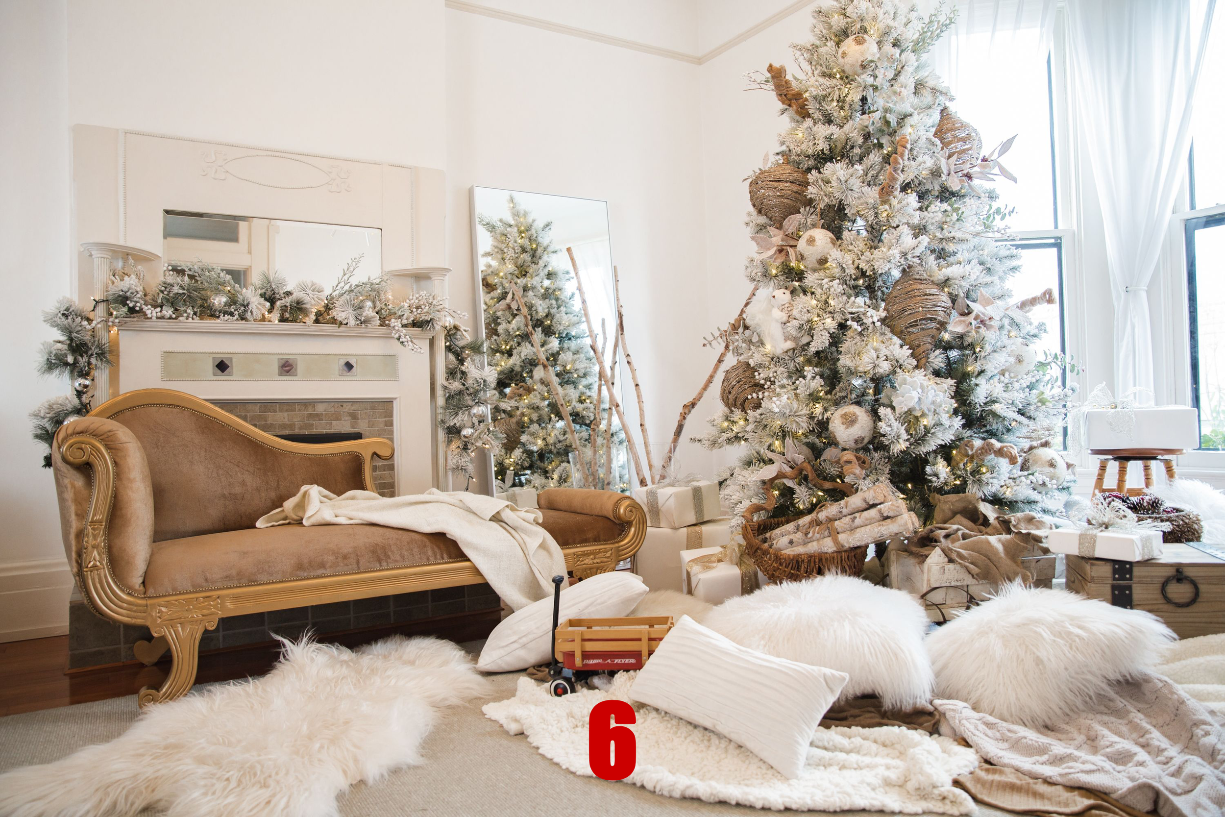 Festively decorated living room with a white Christmas tree, fireplace mantel, and various wrapped presents, featuring a cozy and elegant holiday setup.