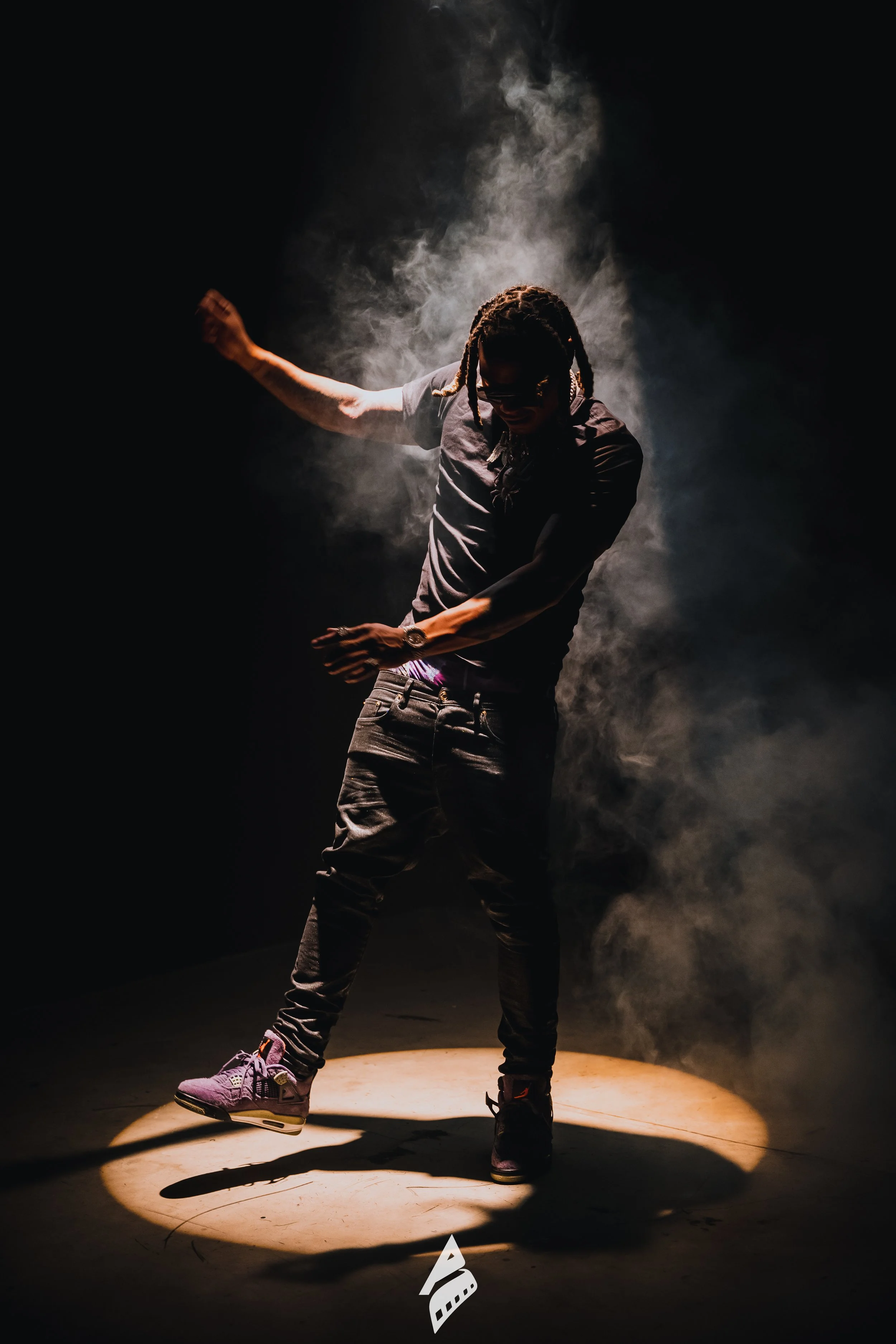 Full-length portrait in smoke and a warm spotlight.