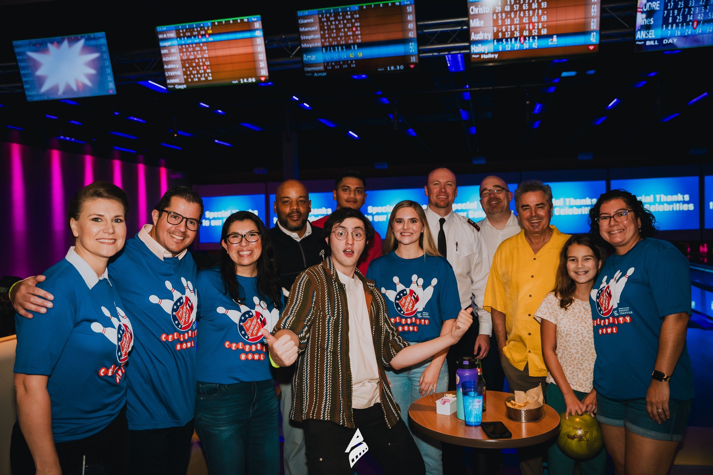 Group portrait beneath colorful bowling venue lights.