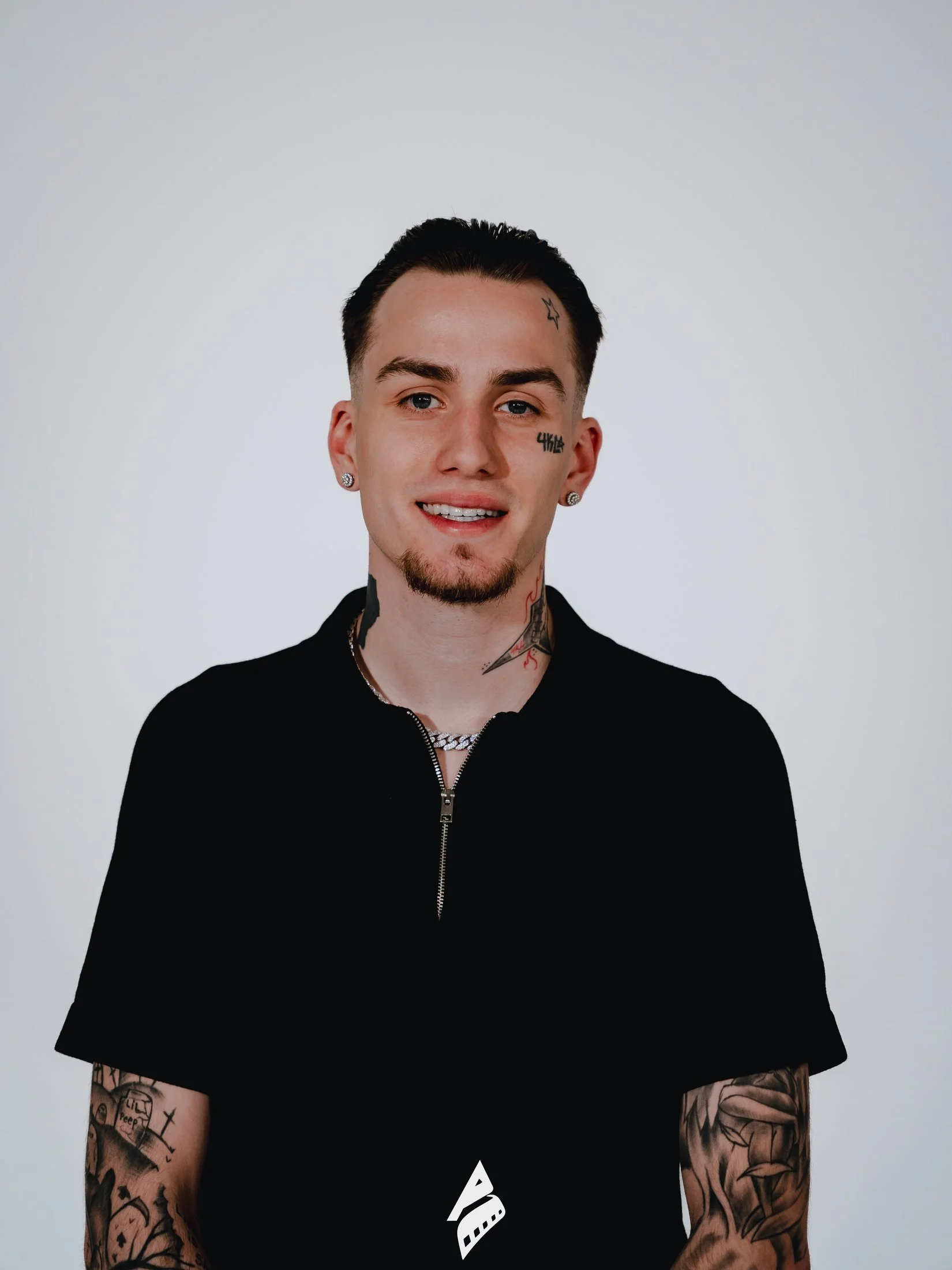 Smiling man in a black shirt against a gray studio background.