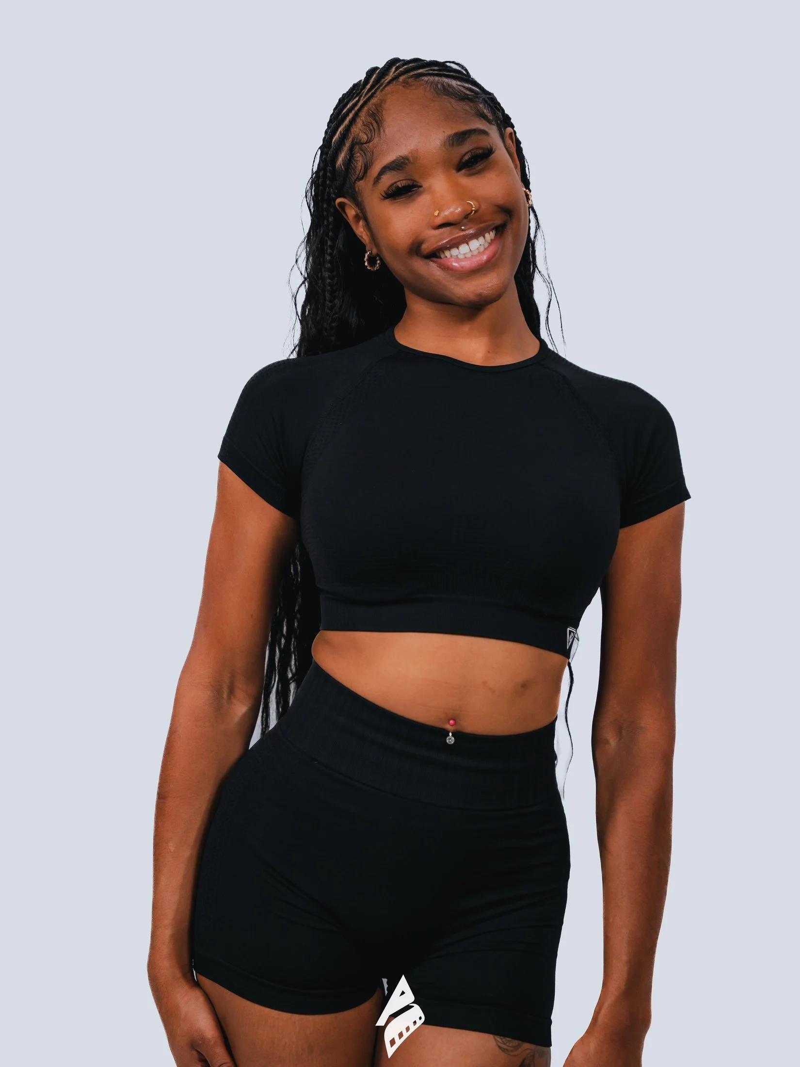 Smiling woman in a black outfit against a light gray studio background.