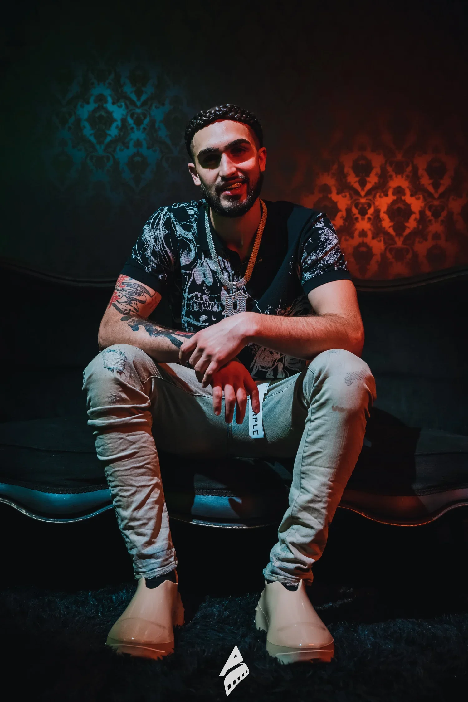 Seated artist portrait against red and blue studio lighting.