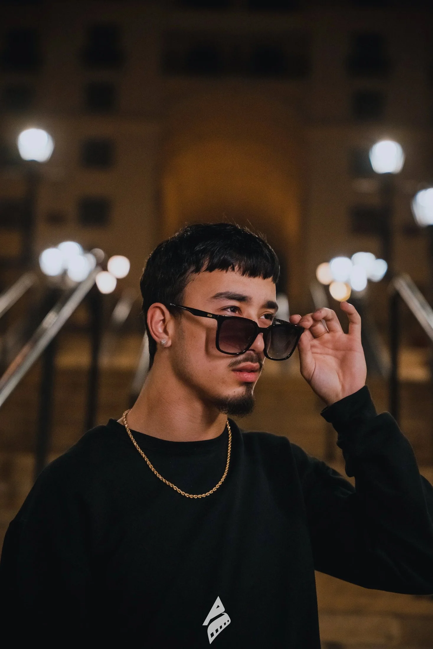 Man adjusting his sunglasses outdoors at night.