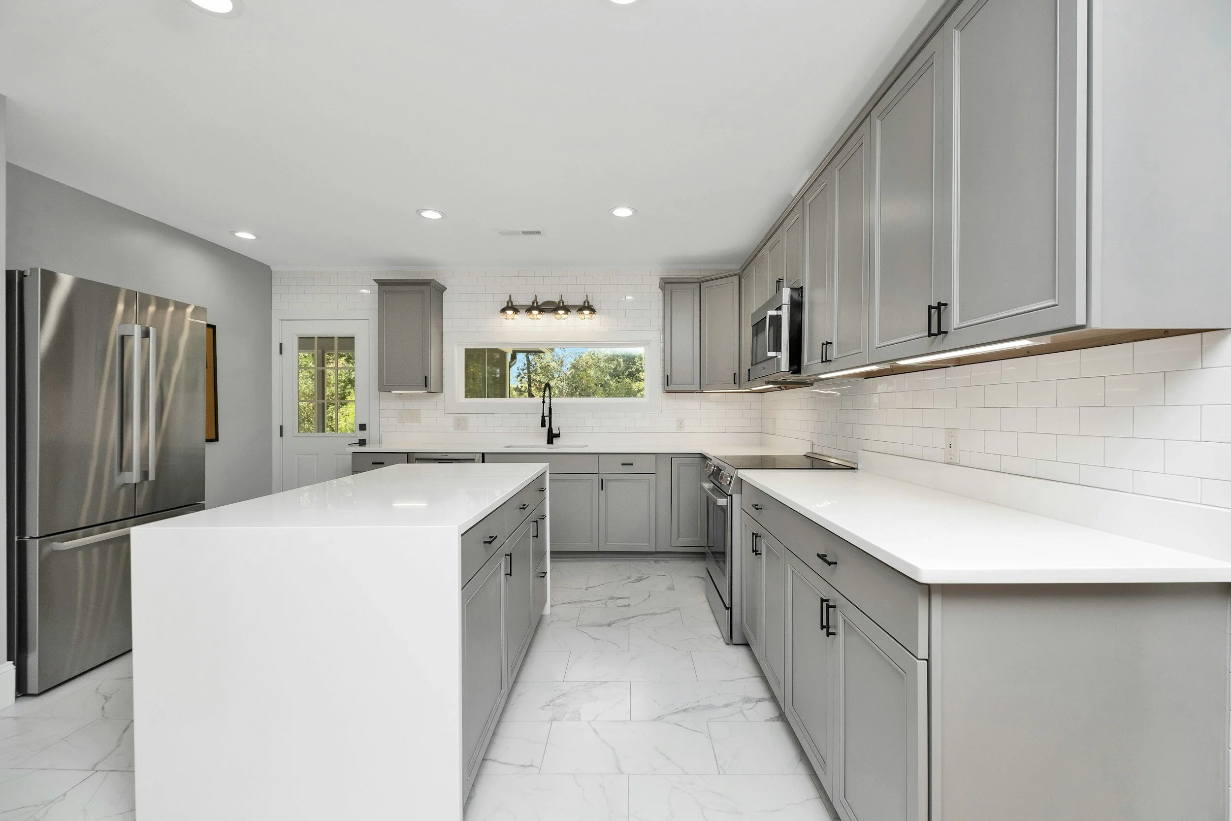 modern updated kitchen. quartz top waterfall edge island top. gray shaker style cabinets