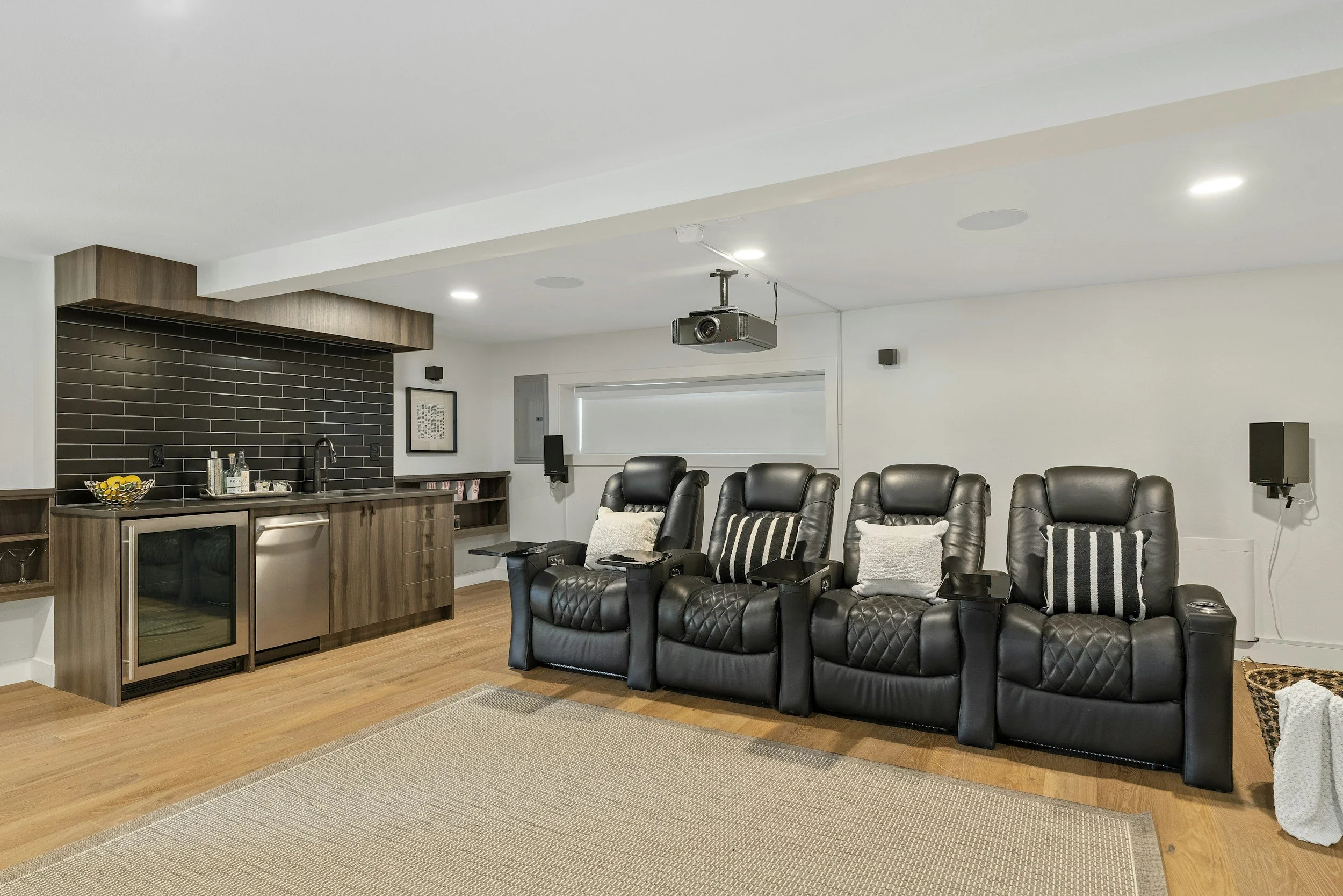 Entertainment basement build out. theatre style seating with ceiling mounted projector. mini kitchen with sink and dishwasher