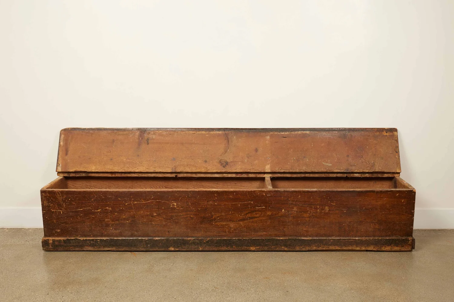Antique long wooden storage bench with open lid, showing rustic patina and warm wood tones.