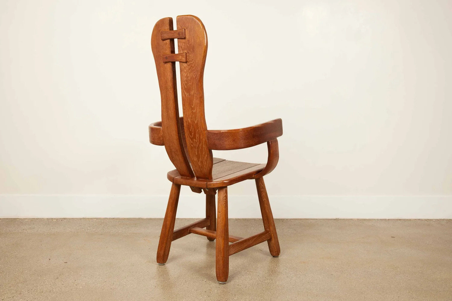 Vintage sculptural solid wood armchair with a high split back, photographed from behind.