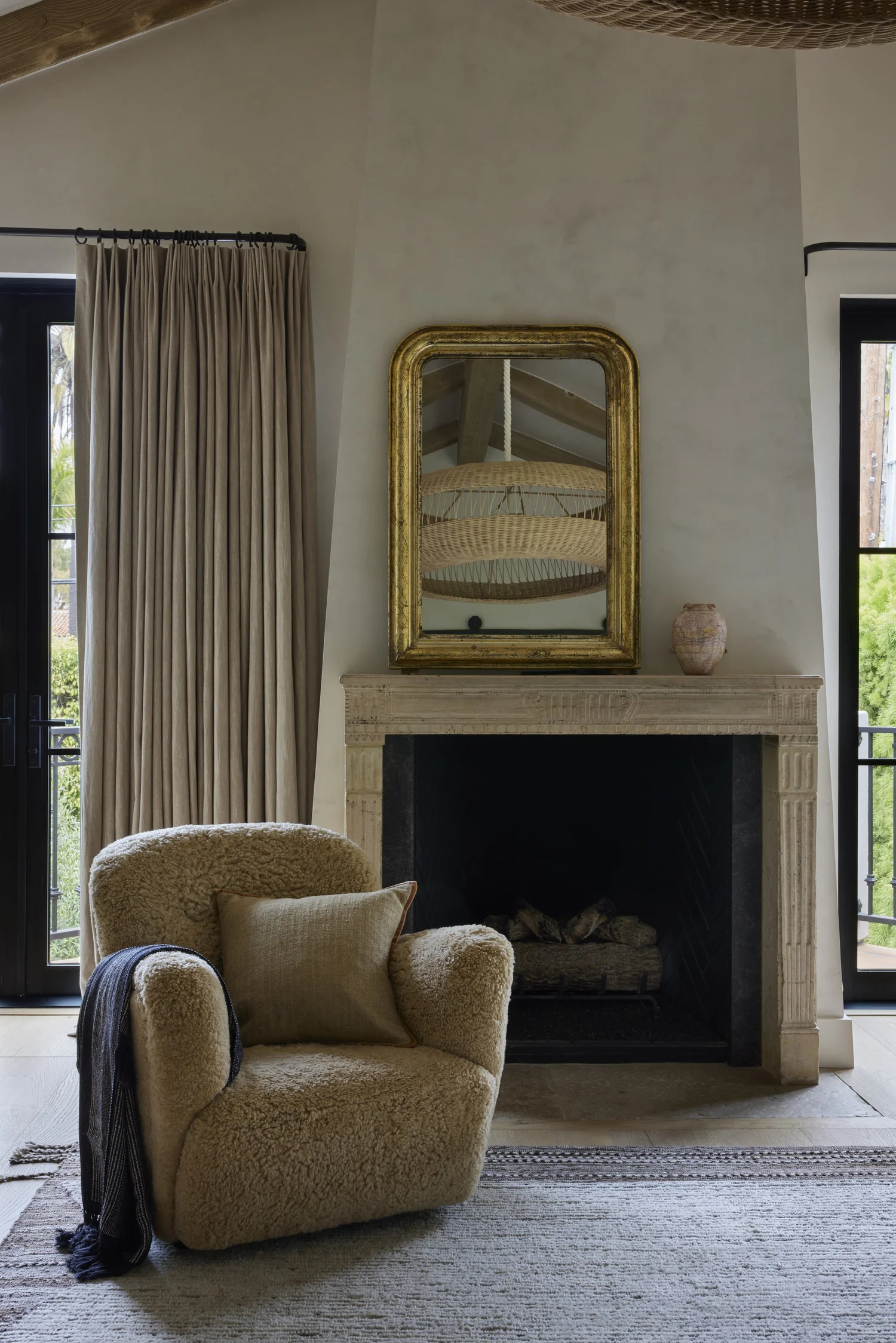 Neutral living room with boucle chair and stone fireplace.