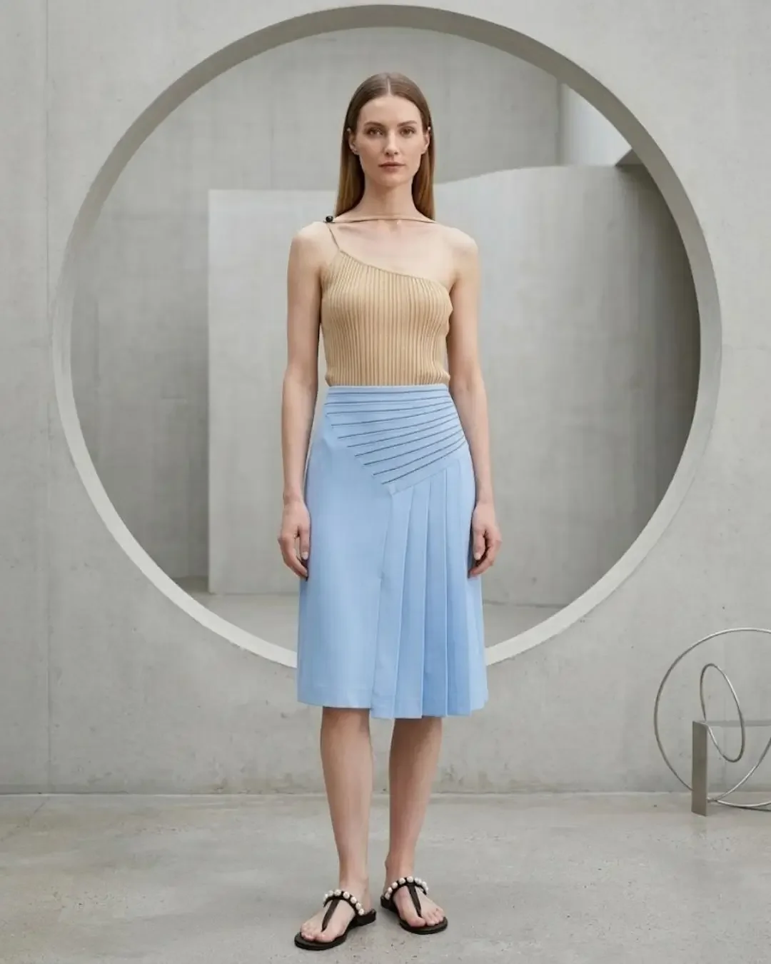 One-shouldered beige ribbed knit top with light blue pleated skirt — Gala-inspired warm tones, Wonder Wardrobe spring capsule wardrobe 2026.