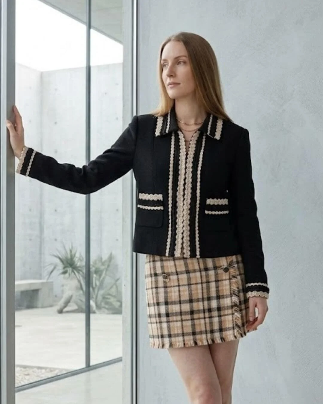 Structured black jacket with cream trim paired with plaid mini skirt — petite capsule wardrobe jacket hitting at mid-hip for balanced proportions